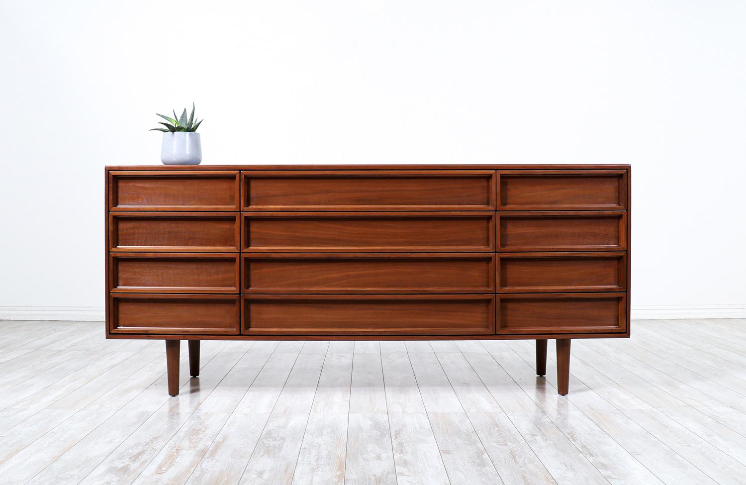Mid-Century Modern dresser designed by John Keal for Brown Saltman in the California circa 1950’s. This minimalist dresser features a walnut wood case with twelve drawers and sits on sculpted tapered legs. The table has been professionally