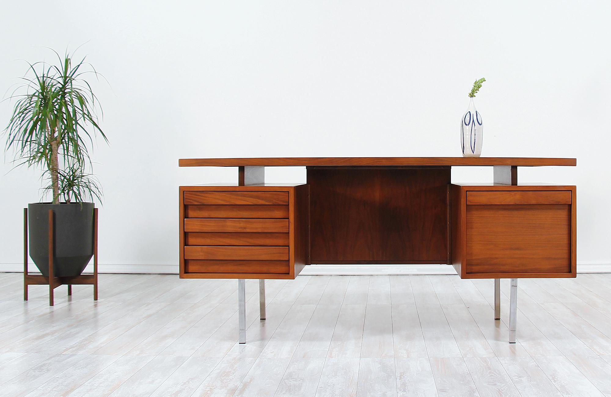Stylish modern executive desk designed by John Keal for Brown Saltman in the United States circa 1950s. This striking desk is crafted in walnut wood featuring a solid case with chromed steel legs and plenty of storage options that add versatility to