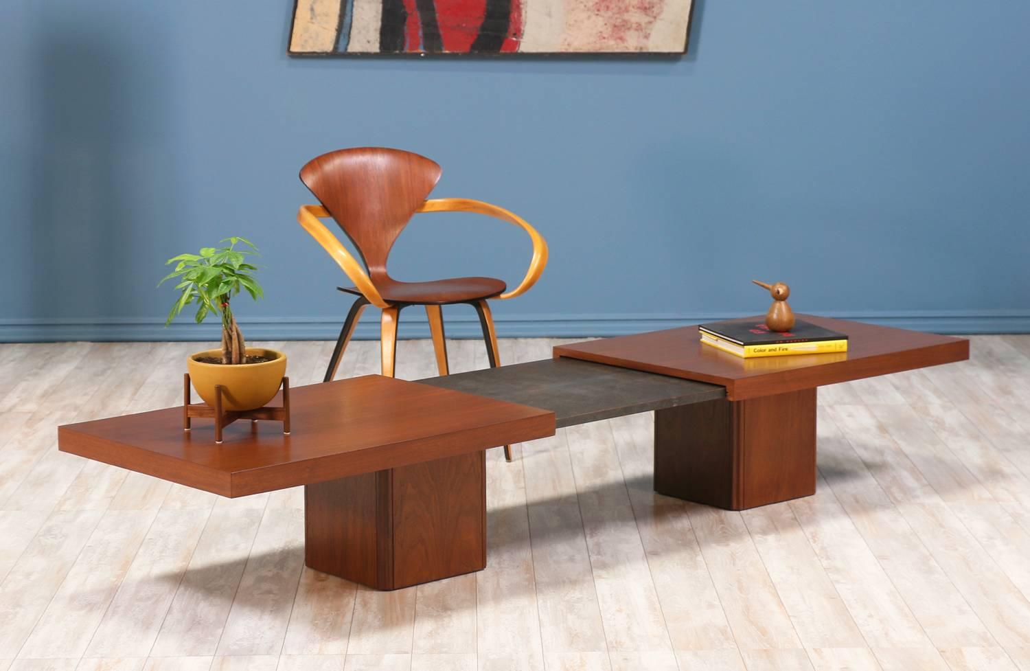 Mid Century modern expanding coffee table designed by John Keal for Brown Saltman in the United States circa 1960’s. This walnut wood coffee table extends up to 96” revealing a dark grey laminate surface in the center. The expandable top sits upon