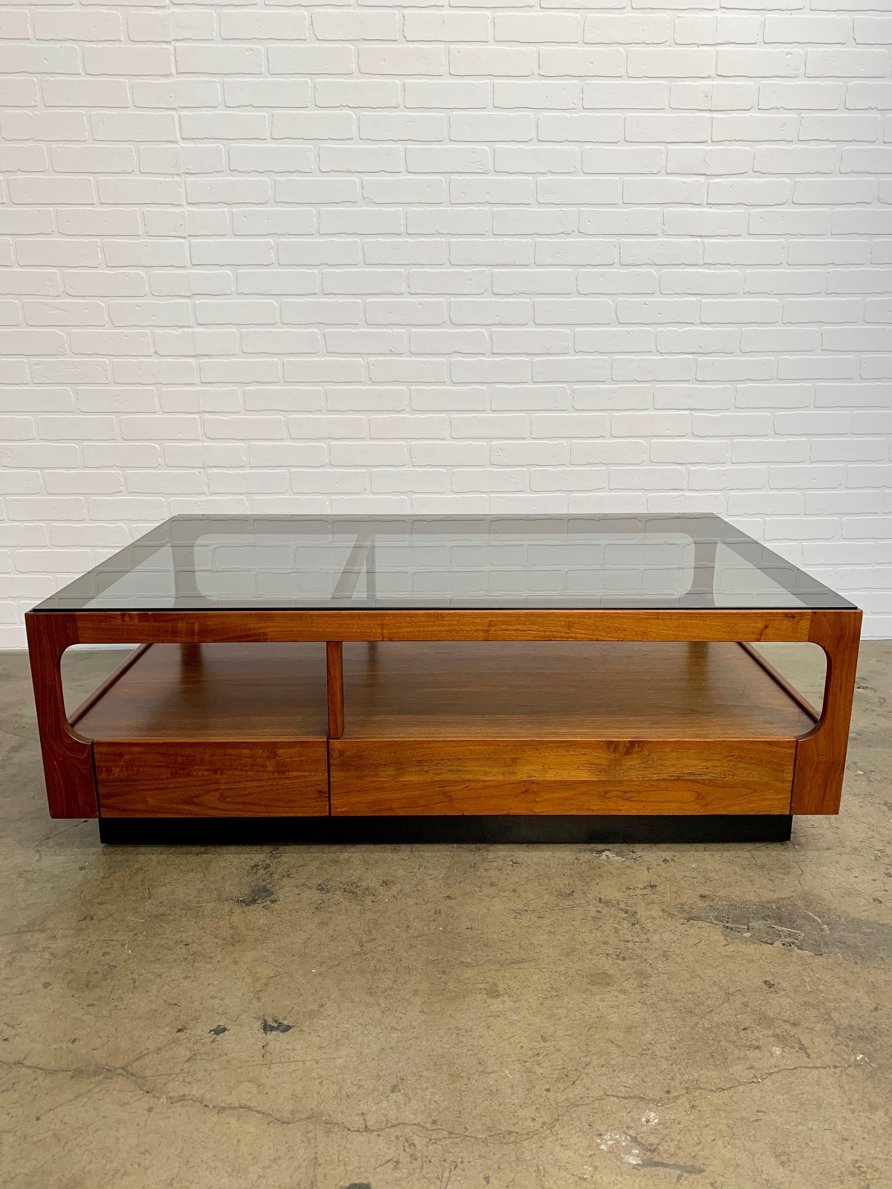 Walnut with smoked glass top, two tiered coffee table that also has two storage drawers.