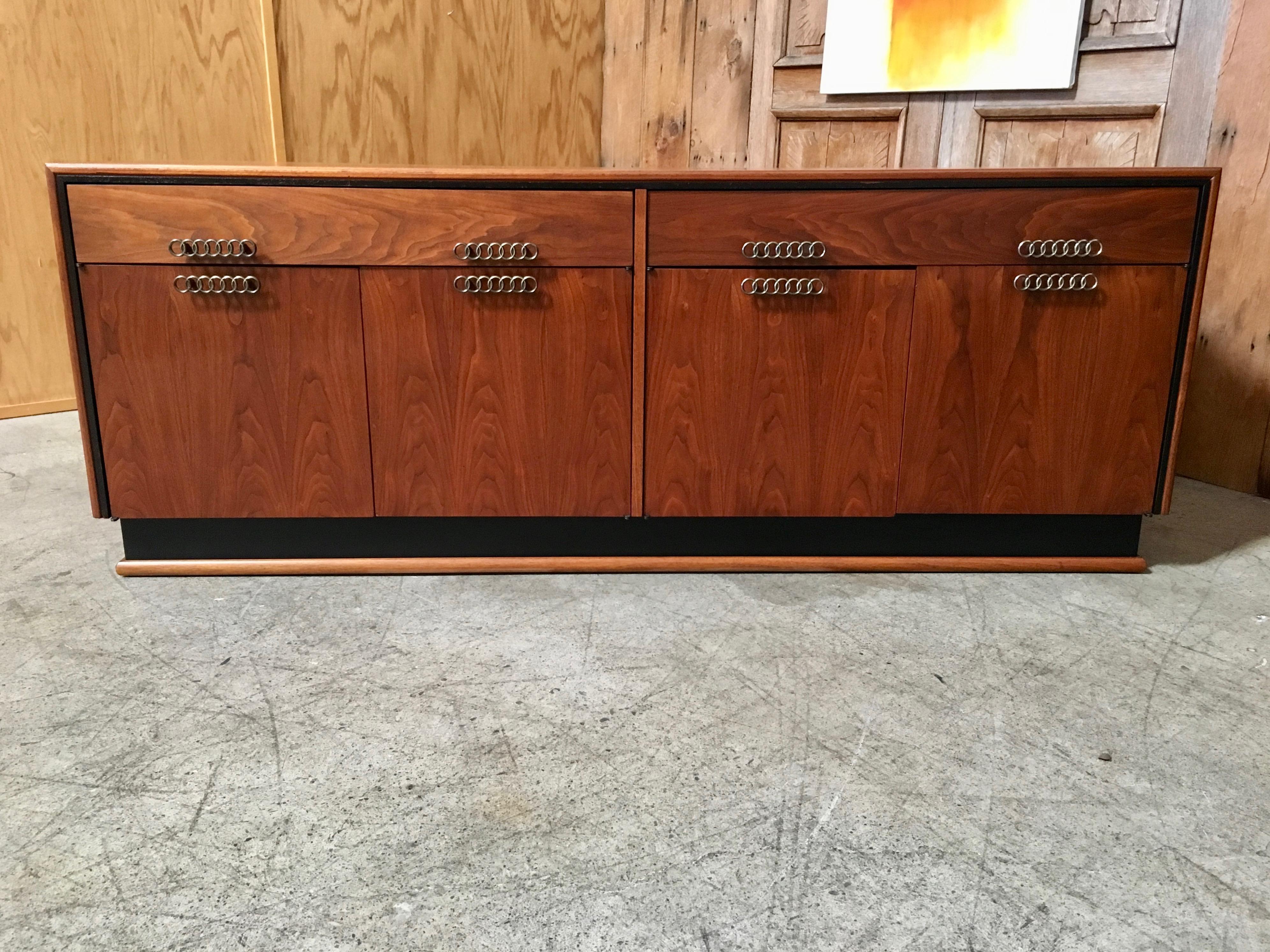 Stunning walnut with black accents two drawers over four doors with seven ring linked drawer pulls and adjustable shelves.