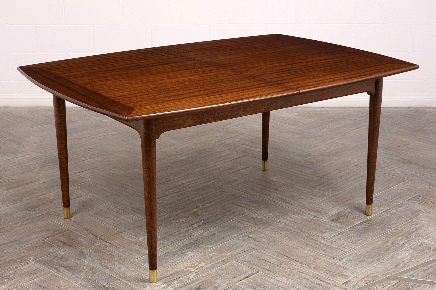 Stunning 1960s John Keal modern dining table for Brown Saltman California. Made from solid walnut wood, newly stained in a rich dark walnut color, with a lacquered finish. Finished with tapered legs and brass toe caps. The table comes with 2 -