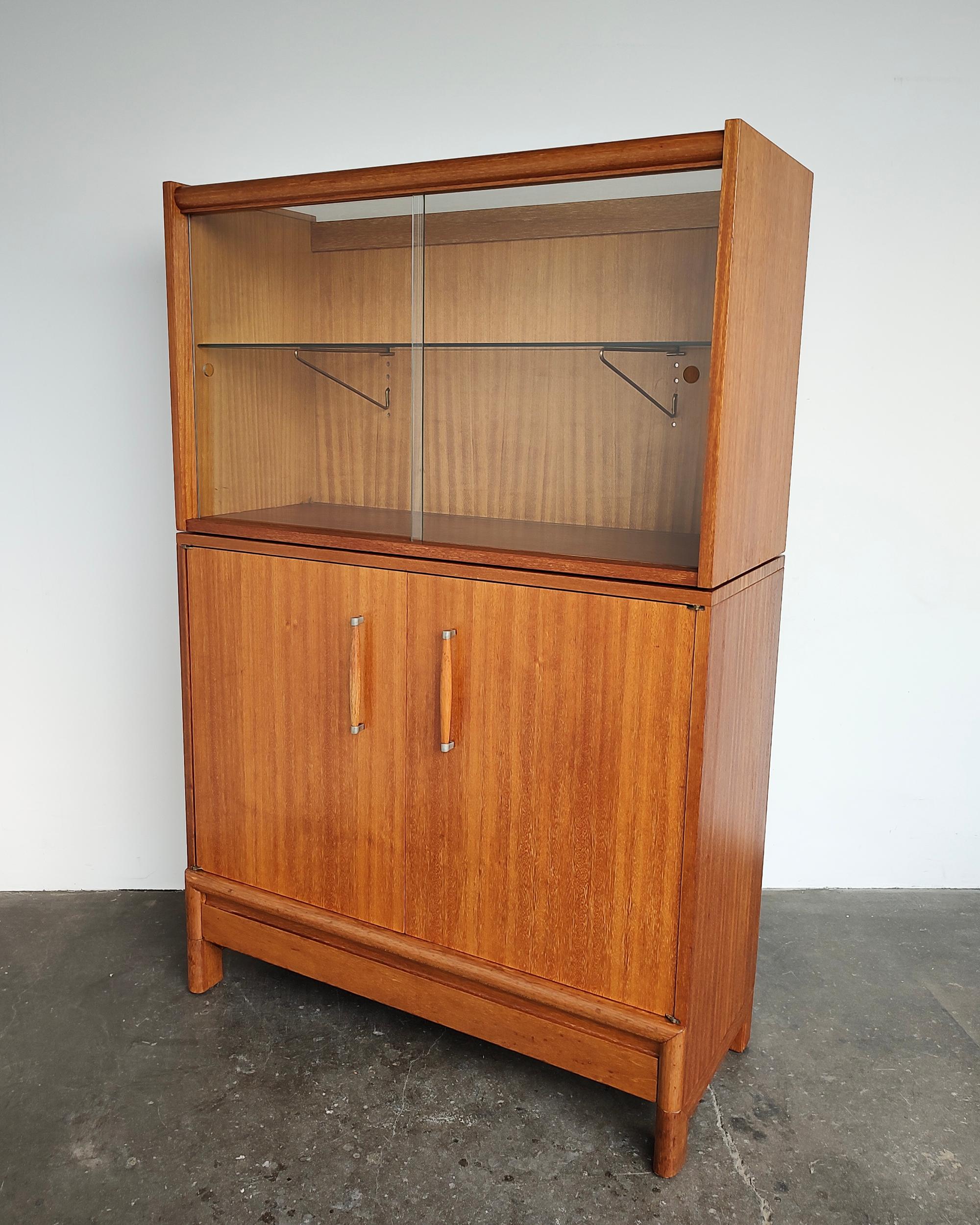 Rare Brown Saltman mahogany cabinet/buffet designed by John Keal. Top features sliding glass doors with adjustable glass shelf inside supported by original brass hardware. Lower cabinet contains fixed shelf with slide-out wine glass rack, and