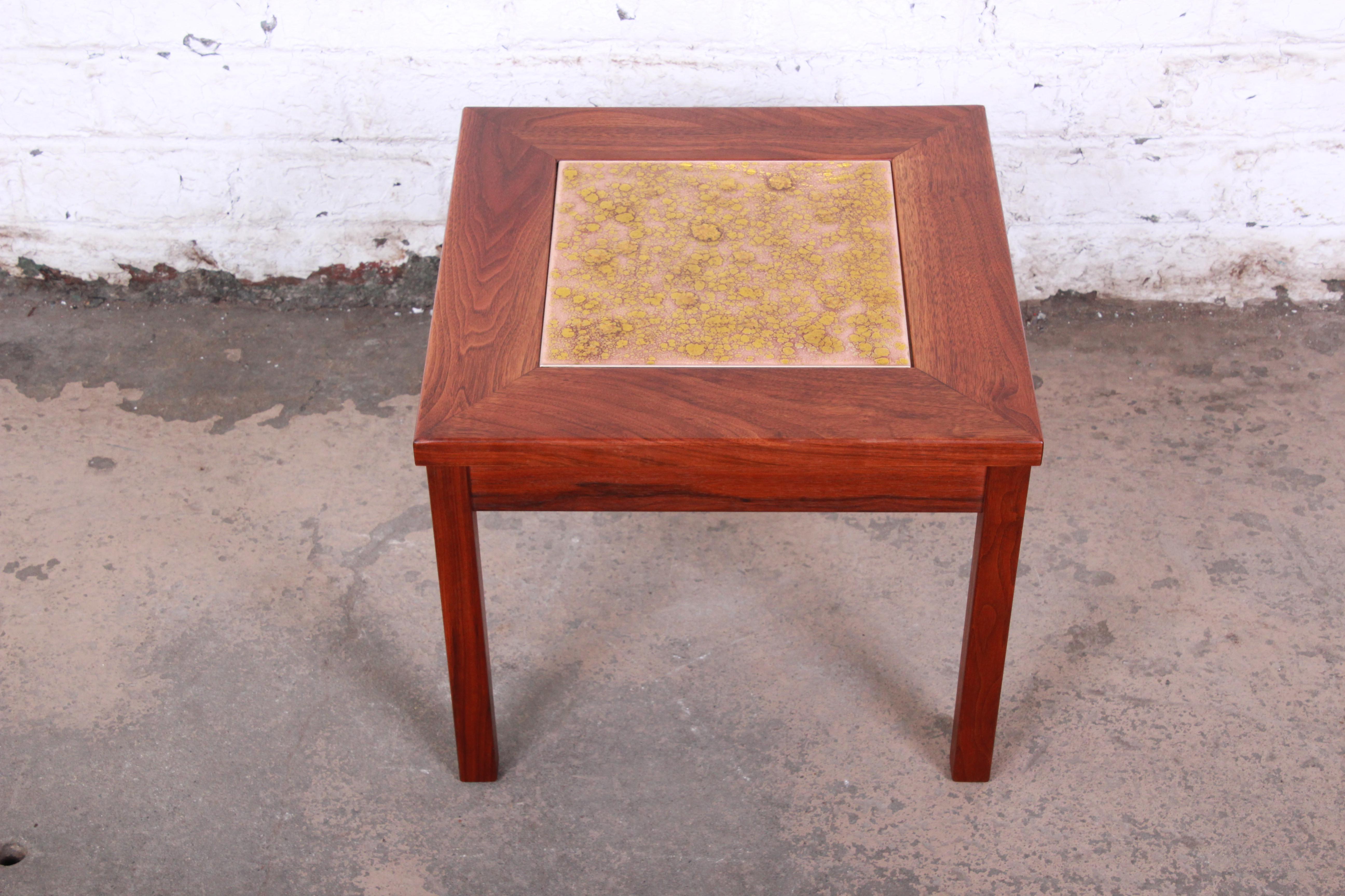 An exceptional Mid-Century Modern side table by John Keal for Brown Saltman of California. The table features gorgeous walnut wood grain and a unique copper tile insert on top. The original label is present on the underside of the table. The table