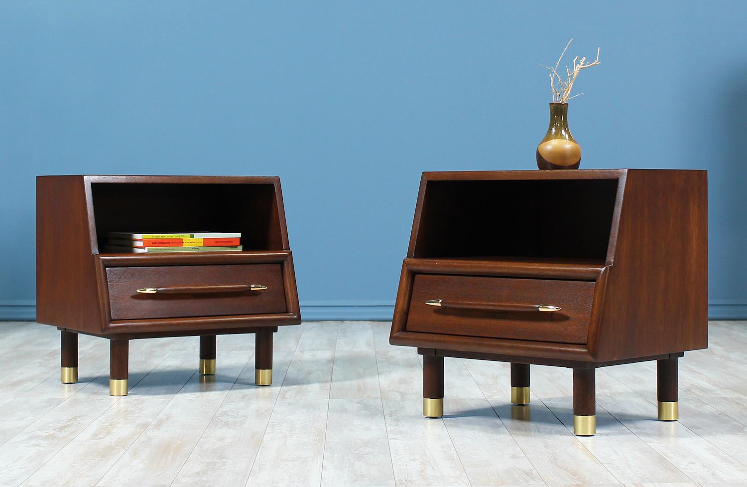 Pair of nightstands designed by John Keal for Brown Saltman in the United States circa 1950’s. This fantastic pair of nightstands are built on solid walnut-stained mahogany wood with beautifully polished brass accents on the leg sabots and the