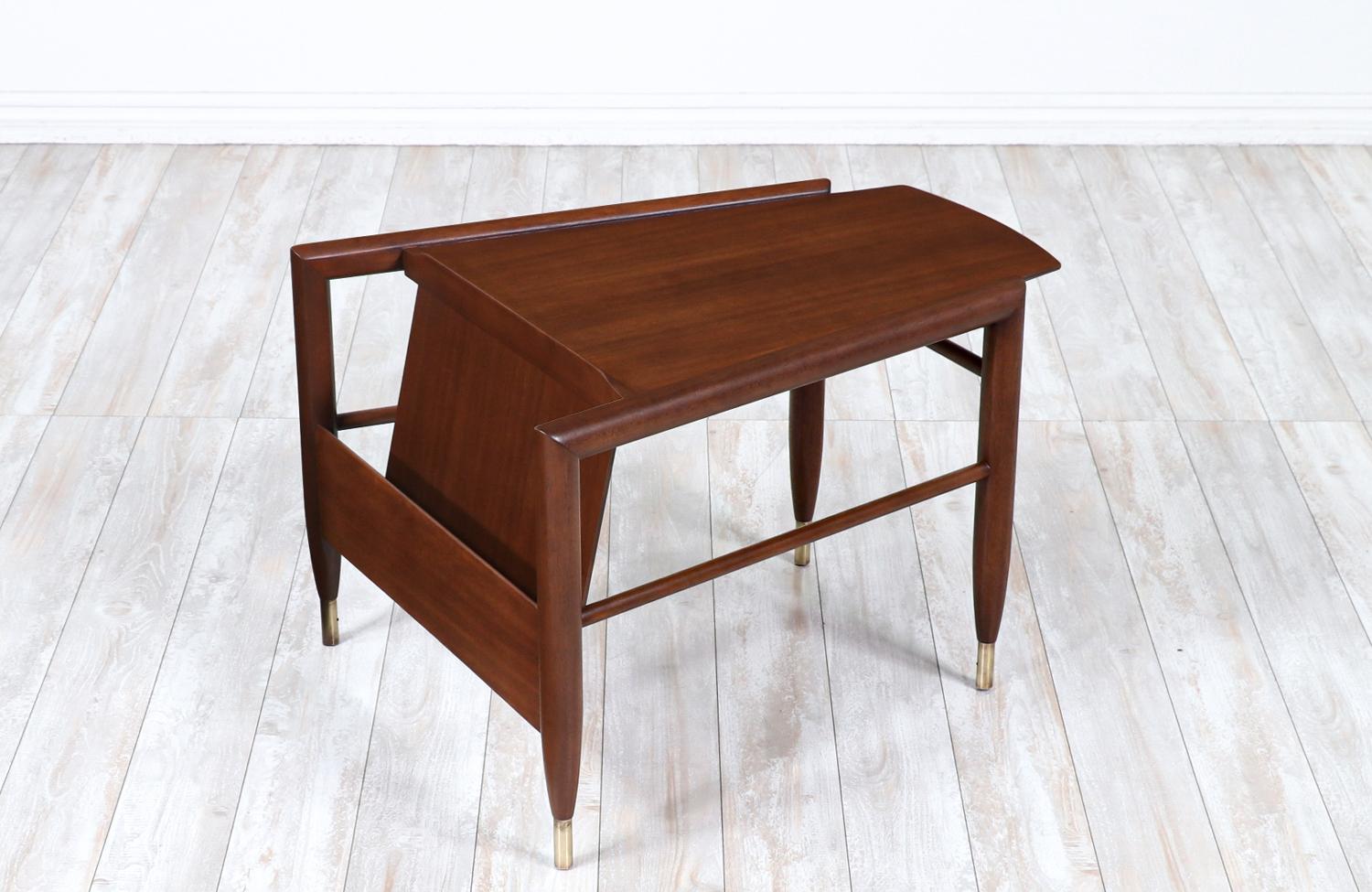 Stylish Mid-Century Modern side table designed by John Keal for Brown Saltman in the United States circa 1960s. This modern side table is crafted in sturdy walnut-stained mahogany with patinated brass sabots in all four legs. The top is complemented