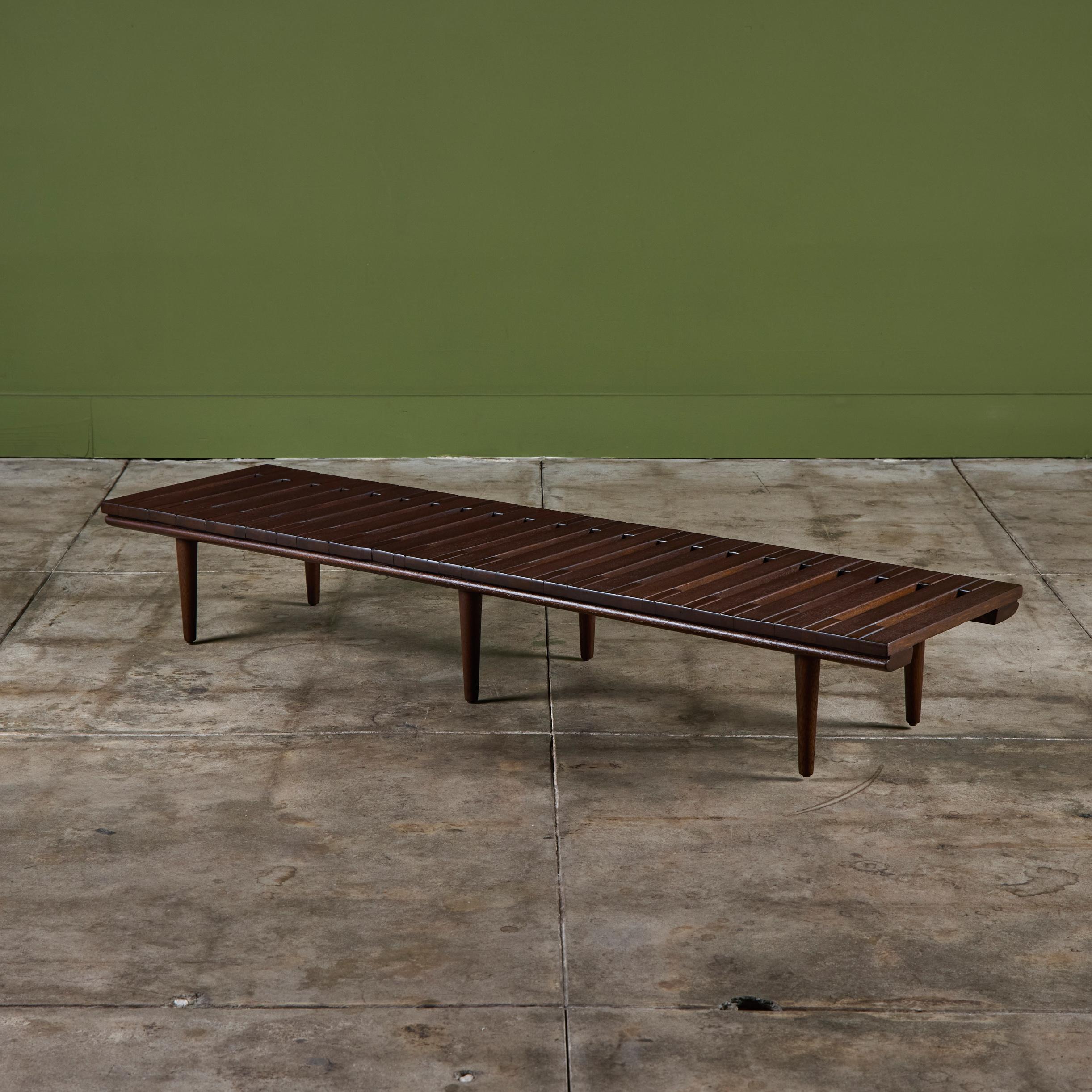 Banco bajo de John Keal para Brown Saltman, hacia la década de 1950, EEUU. El banco tiene listones de madera de caoba y patas de espiga cónicas. Perfecta como mesa de centro de perfil bajo, banco de entrada o colocada detrás de un