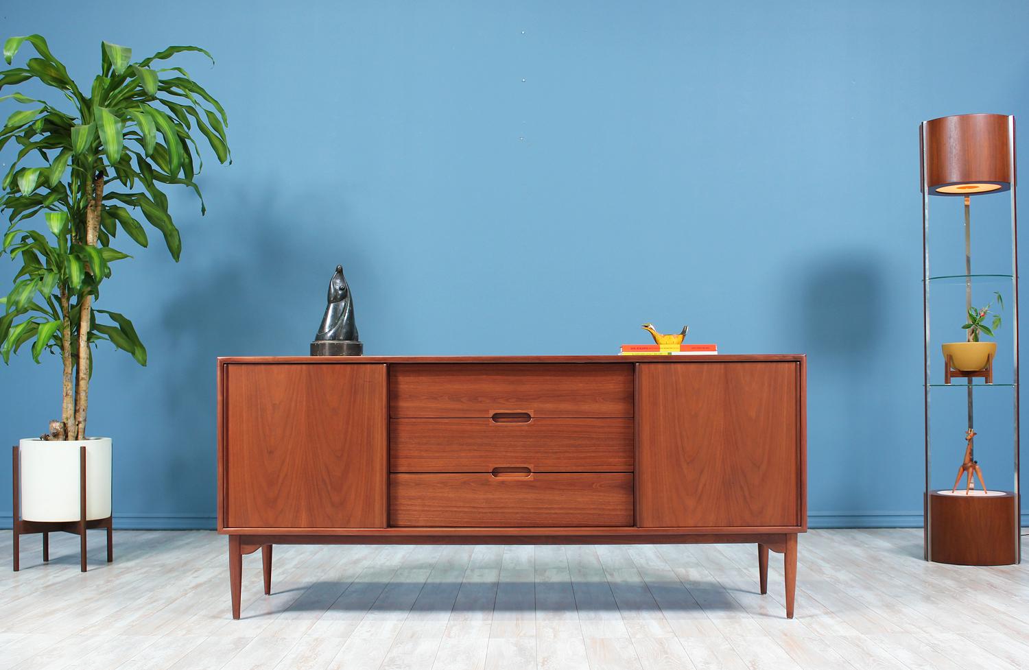 Gorgeous walnut credenza designed by John Keal for Brown Saltman in the United States circa 1950’s. A stunning piece crafted in walnut wood with beautiful grain detail sitting on a sculptural base that adds a playful and organic modern profile. This