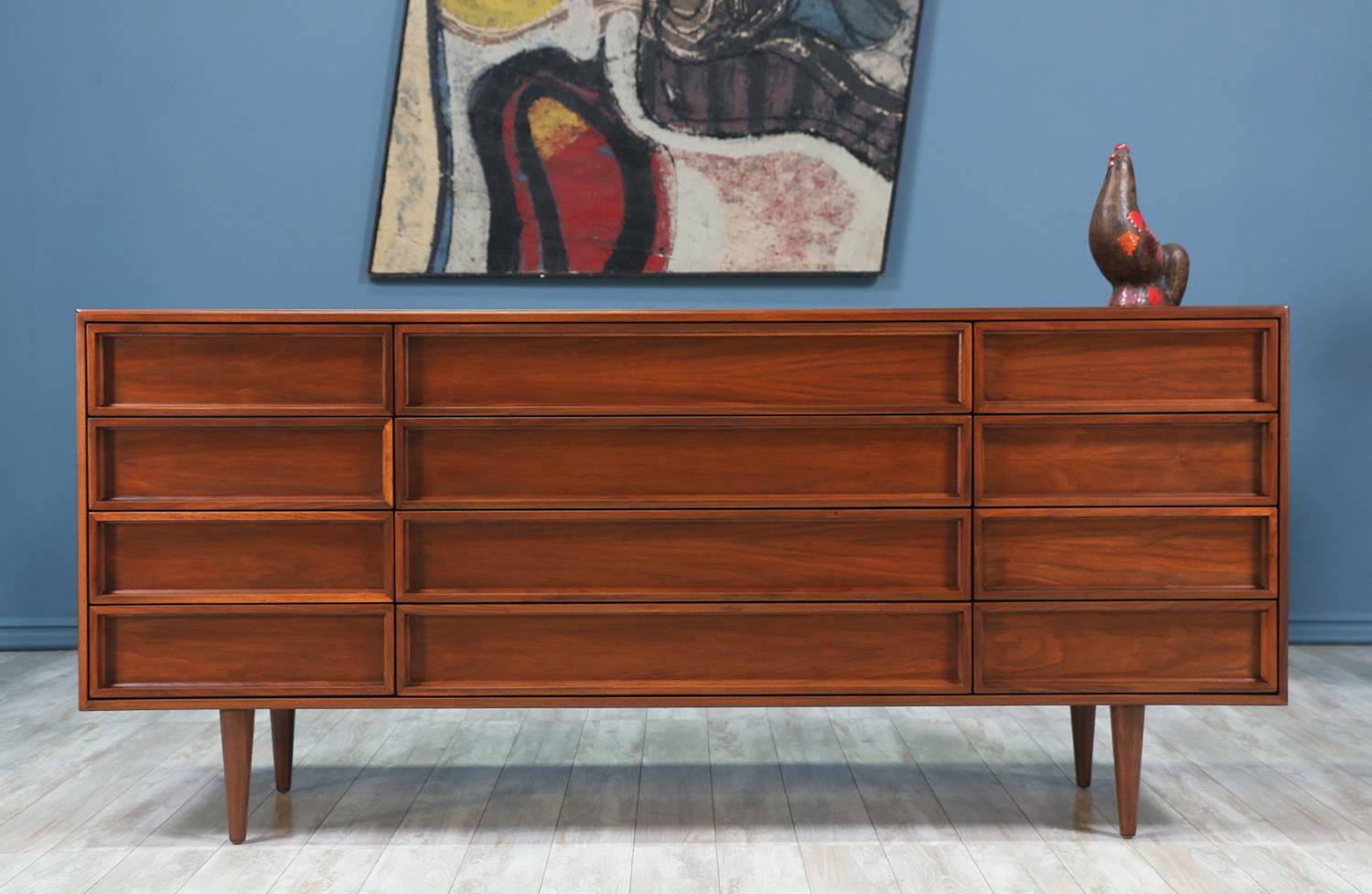 Mid Century Modern dresser designed by John Keal for Brown Saltman in the California circa 1950’s. This minimalist dresser features a walnut wood case with twelve drawers and sits on sculpted tapered legs.