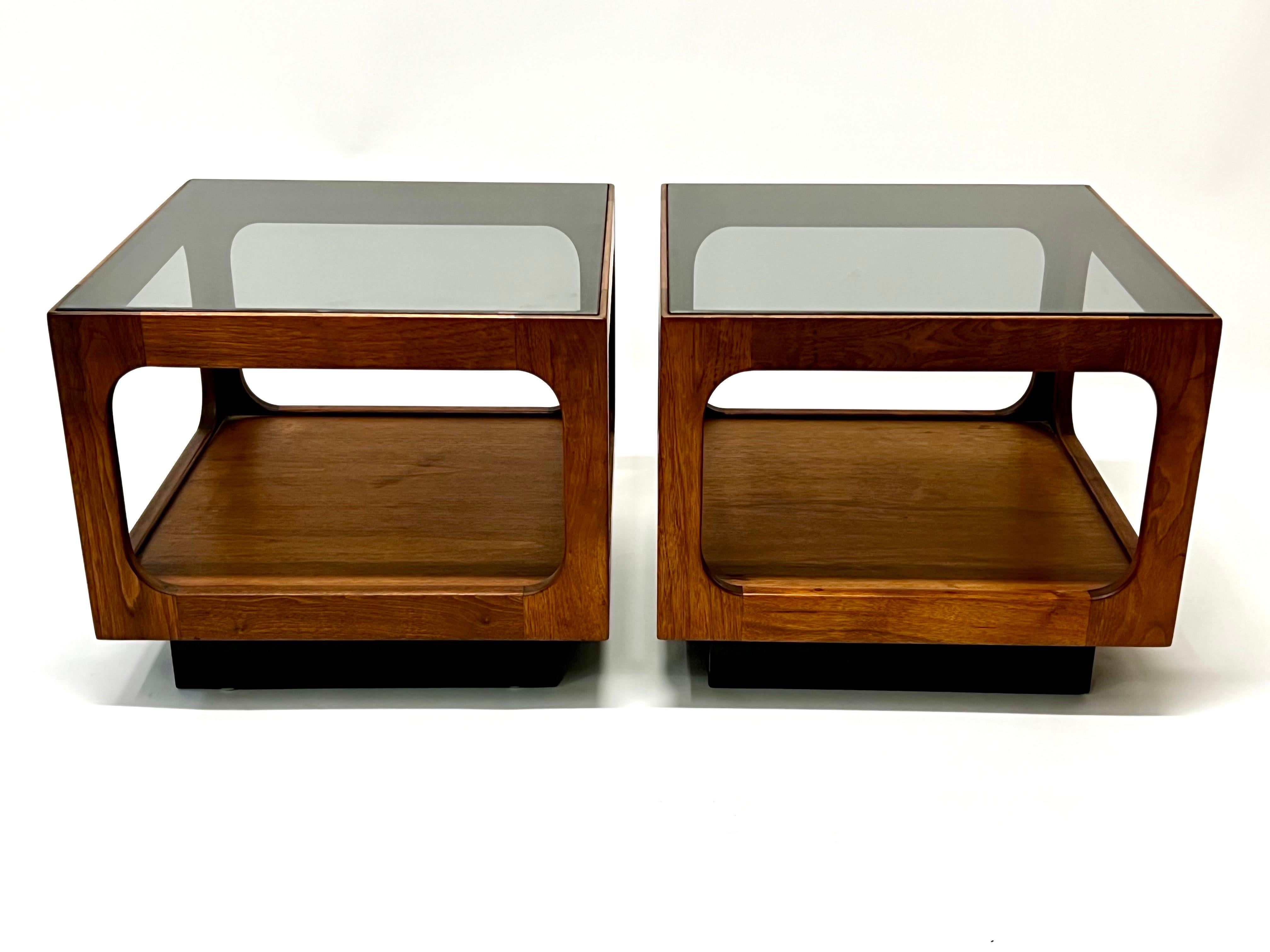 Wonderful pair of walnut side tables or nightstands with original smoked glass tops by California designer, John Keal c1960s. Keal one of a handful of designers who worked for Brown-Saltman from the 1950s to the 1970s. Beautiful walnut cubes on a