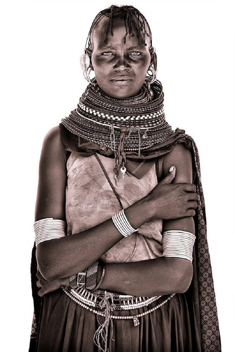Retrato de una hermosa joven turkana fotografiada a orillas del lago Turkana.

John utiliza simplemente luz natural y construye primitivos estudios improvisados con sábanas blancas adquiridas en la zona. La luz difusa le permite captar un notable