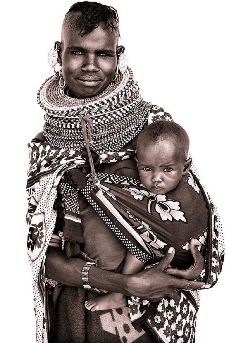 Ayoni und ihr Kind - eine lächelnde Turkana-Mutter.

John nutzt einfaches natürliches Licht und baut primitive Behelfsstudios aus vor Ort erworbenen weißen Laken!  Das diffuse Licht ermöglicht es ihm, eine bemerkenswerte Detailgenauigkeit