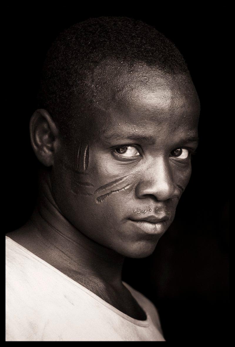Dieser Tamberma-Mann stammt aus einem kleinen Dorf namens Nadoba in Togo, etwa zehn Kilometer von der Grenze zu Benin entfernt.   Das Dorf ist bekannt für seine Gesichtsskarifikationen. 

 Ein feuriger Wind wehte von den umliegenden Tiefebenen über