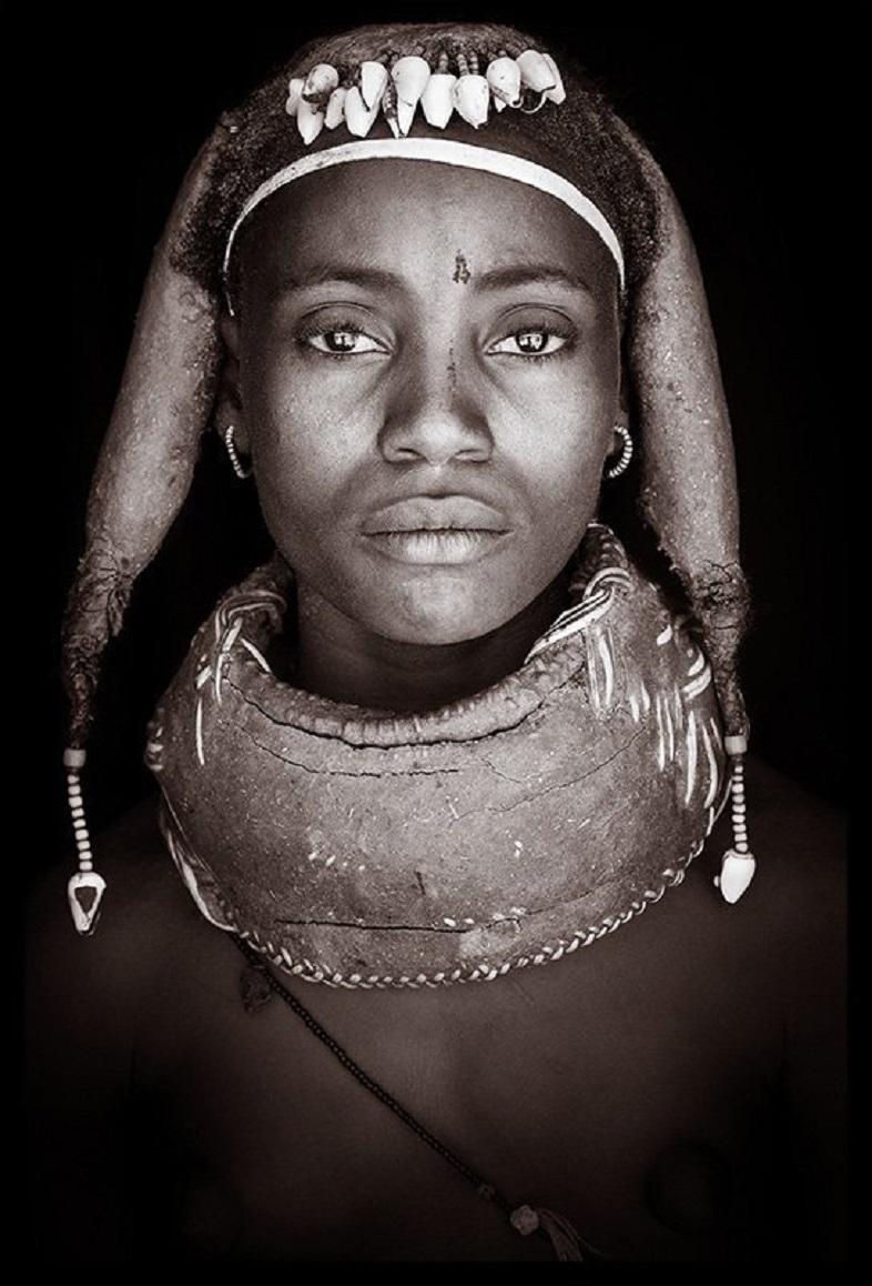 Junge Mumuhuile-Frau aus der Region Huile im Süden Angolas.

John Kennys Arbeiten werden alle vor Ort in einigen der entlegensten Ecken Afrikas gedreht. Seine Bilder werden alle mit natürlichem Licht und in der Alltagskleidung seiner Motive