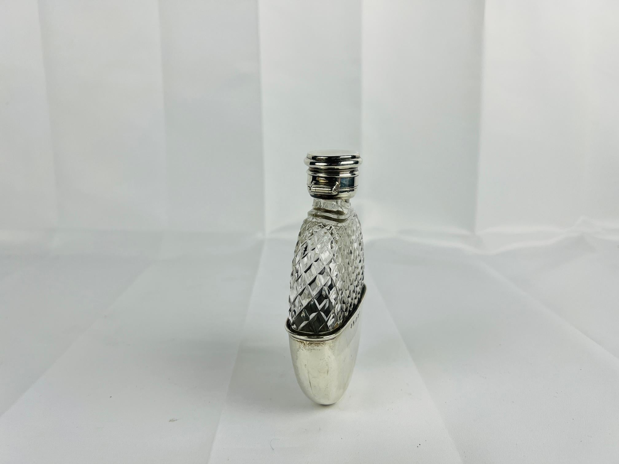 This exquisite Sterling Silver and Cut Glass Locking Hip Flask, crafted by renowned London silversmith John Linegar circa 1877, epitomizes the elegance and craftsmanship of the late Victorian era. This remarkable piece seamlessly blends luxurious