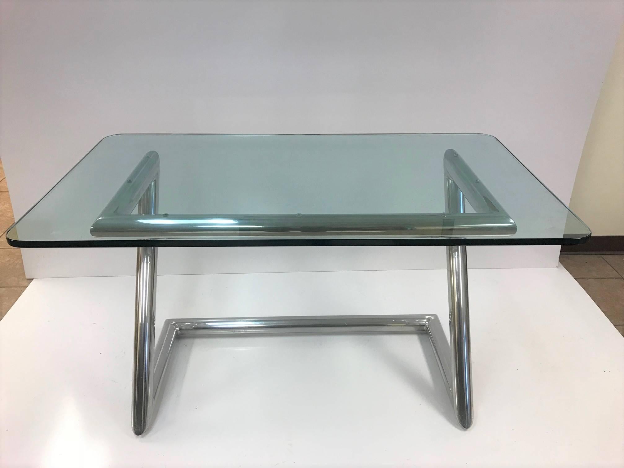 John Mascheroni polished aluminum and glass desk. Desk has a tubular frame with a 1/2 inch thick glass top.