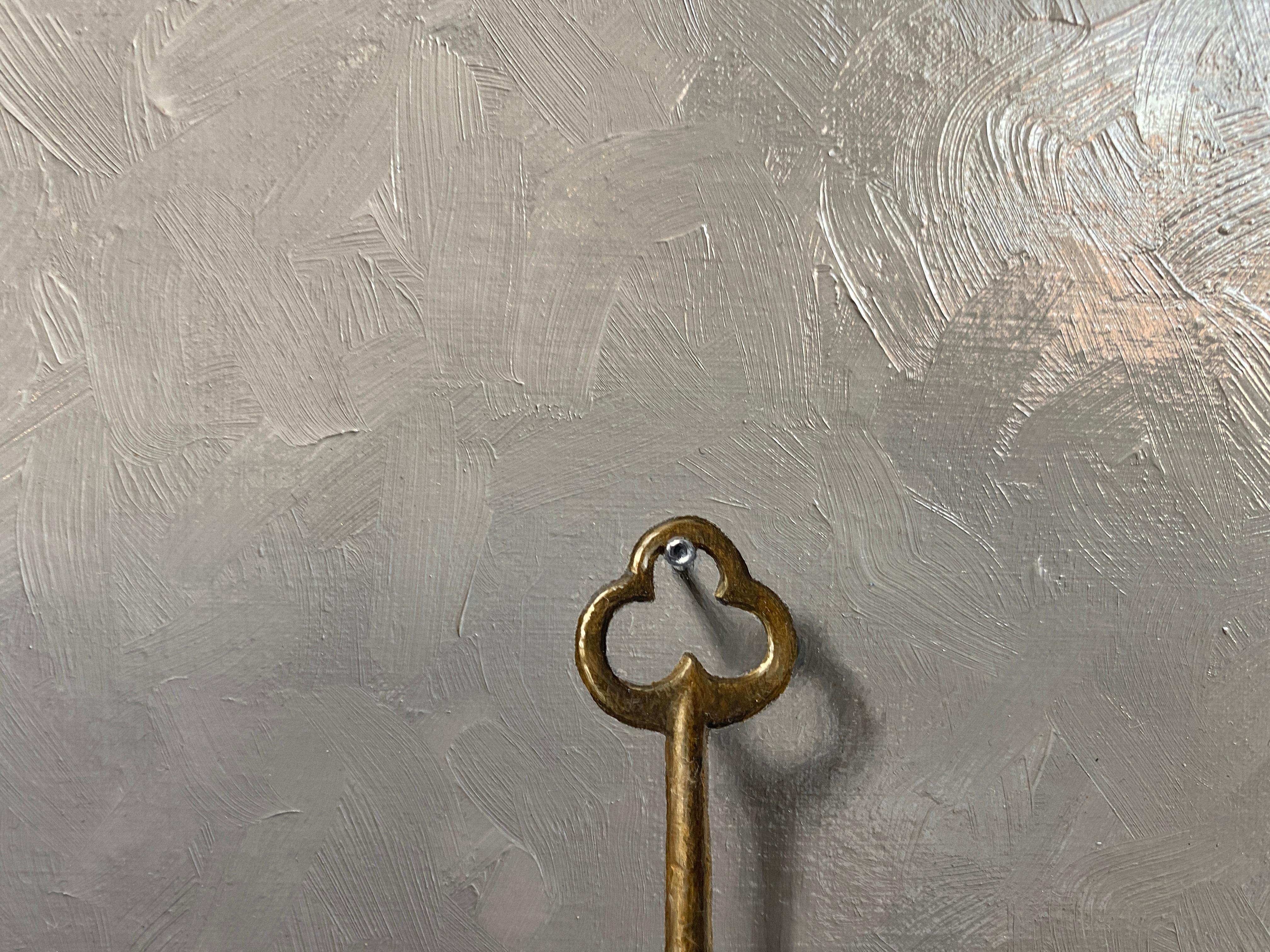 An oil painting of a gold antique key, hanging from a nail, against a grey background. Painted in the realist style, a trompe l'oeil, or to trick the eye. Brushstrokes can be found in the background. 

Painting dimensions: 9 x 7 inches
Framed