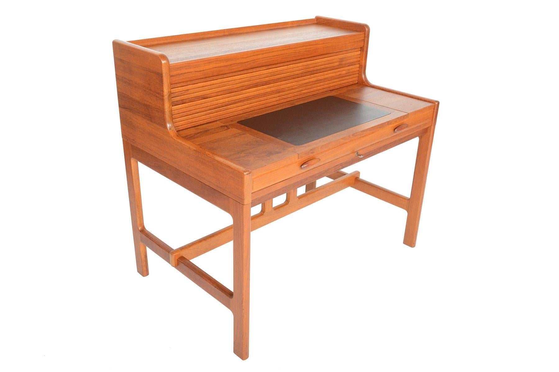 Ce bureau moderne danois en teck a été conçu par John Mortensen pour Dyrlund. Un savoir-faire exceptionnel et une construction en teck massif mettent en valeur son design dynamique ! La surface du bureau se tire vers l'avant pour soulever une porte