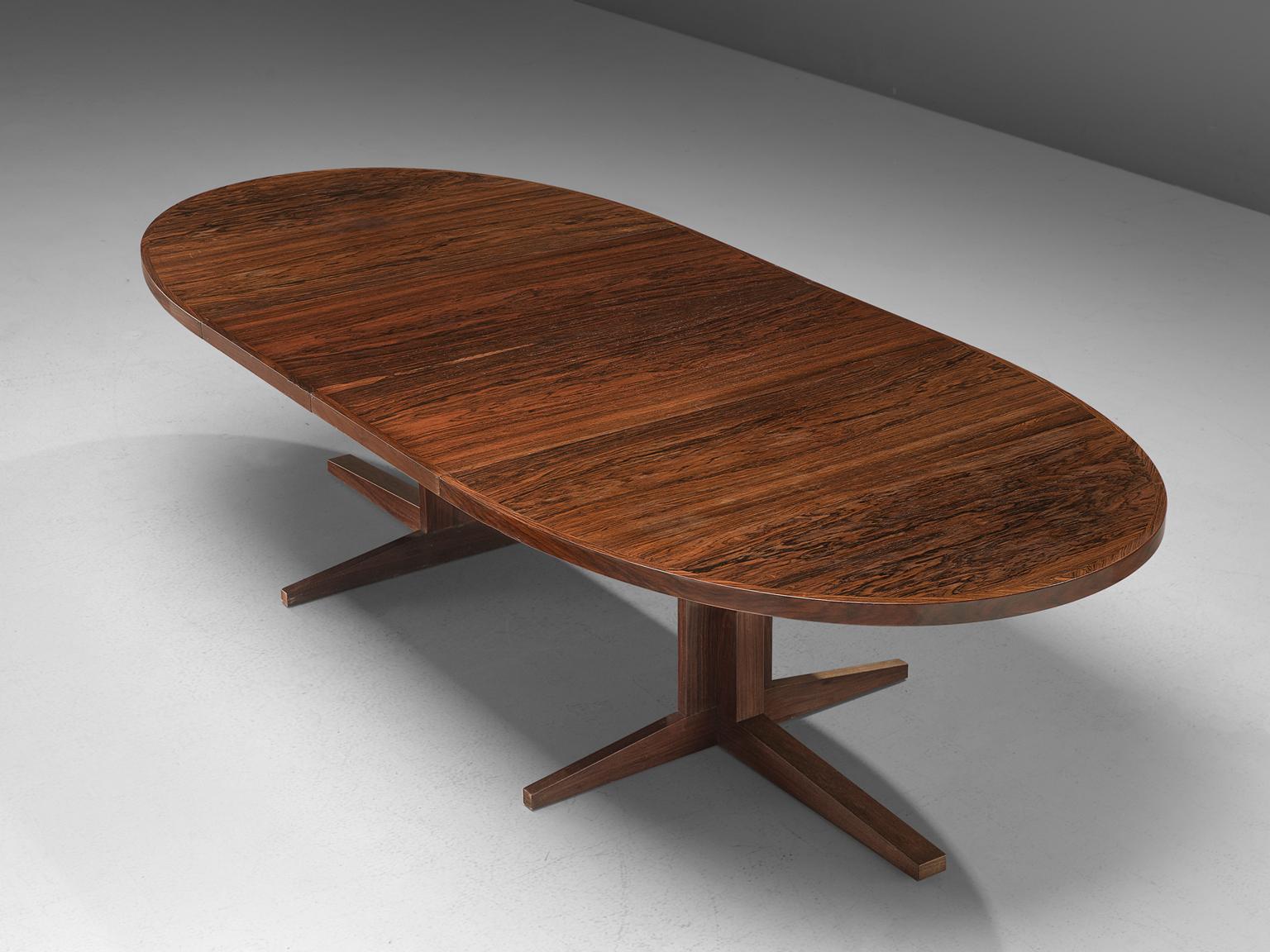 John Mortensen for Heltborg Møbler, dining table model HM55, rosewood, Denmark, 1960s. 

Large oval dining table with 2 leafs. This table has a very interesting base. In small position the legs form a cross with four points. When extended the