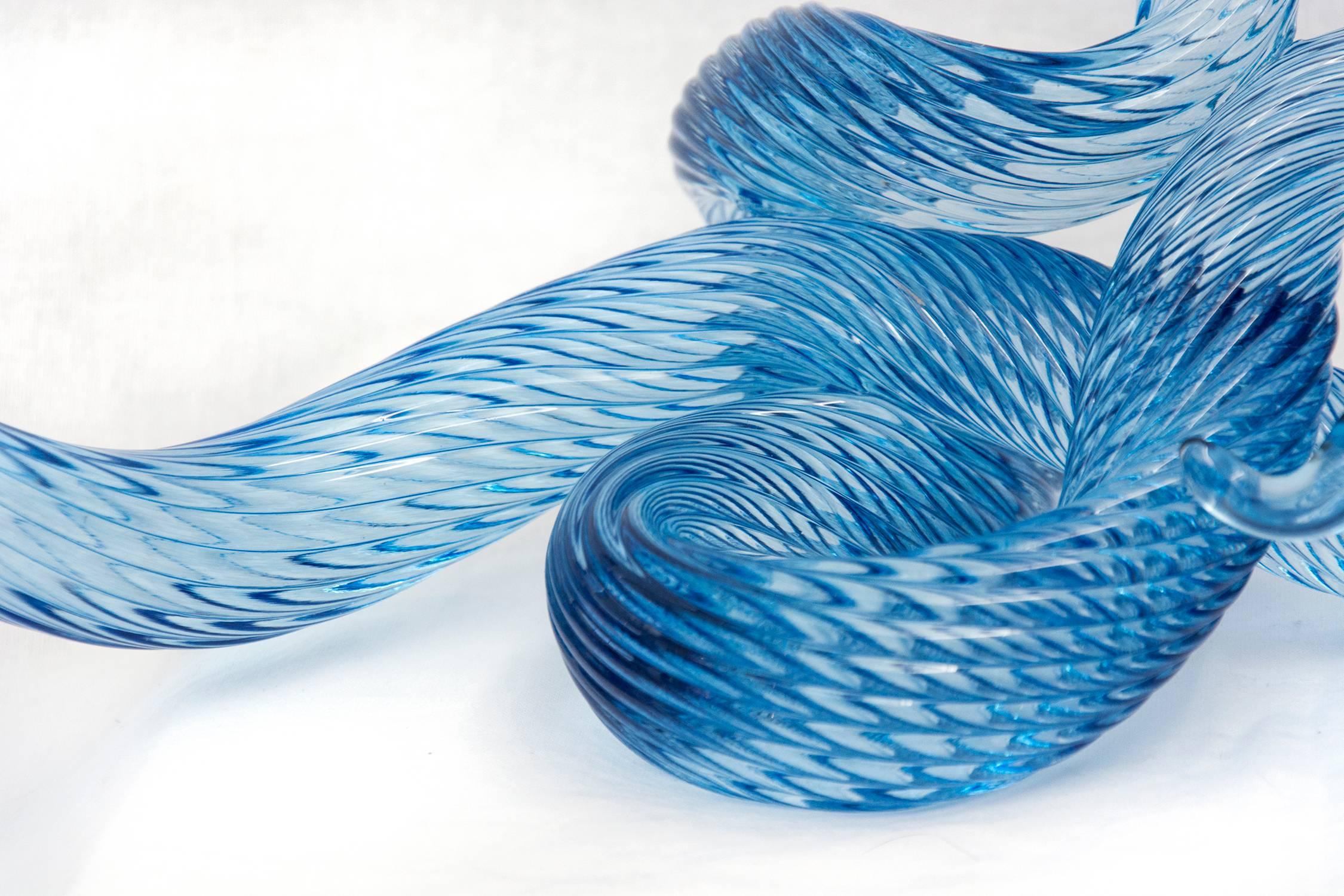 Three rods of translucent and striated cerulean blue glass are twisted, looped and shaped into elegant waves by artist John Paul Robinson. The curated three part design is enhanced by light that sparkles on the complex surfaces of this table top