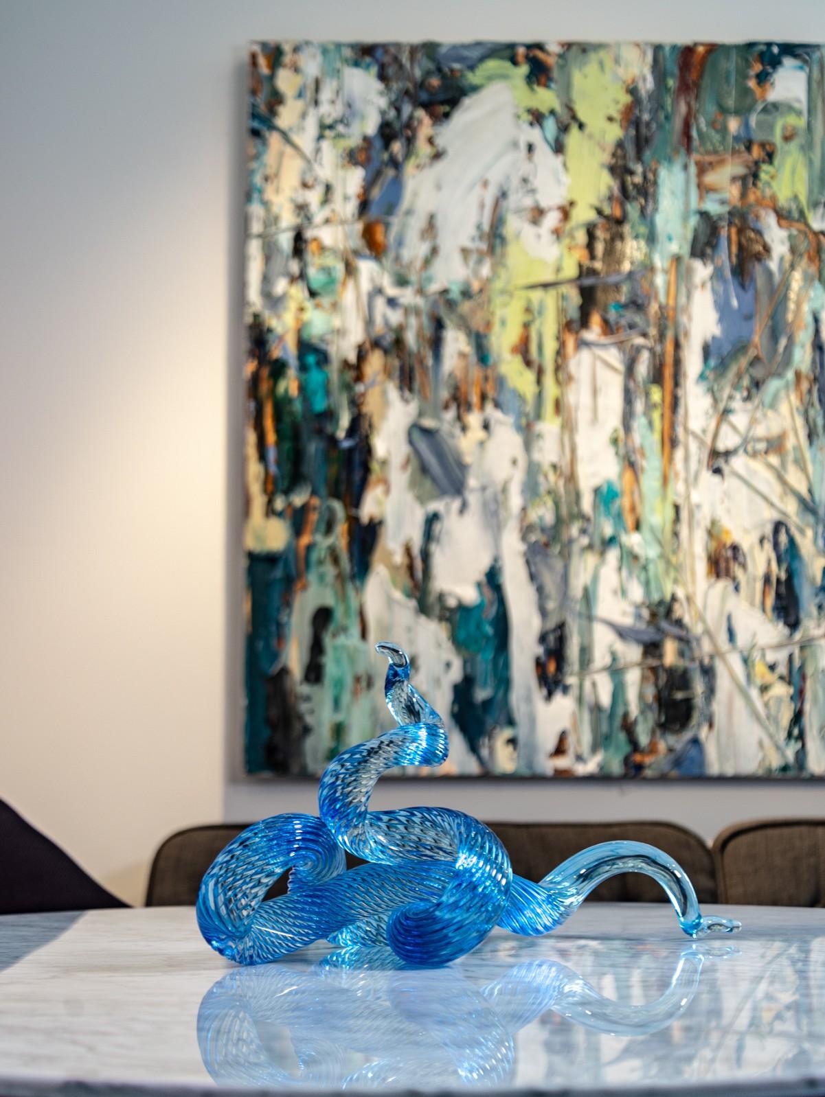 A single rod of translucent and striated marine blue glass is twisted, looped and shaped into an elegant wave by artist John Paul Robinson. The design is enhanced by light that sparkles on the complex surfaces of this table top sized