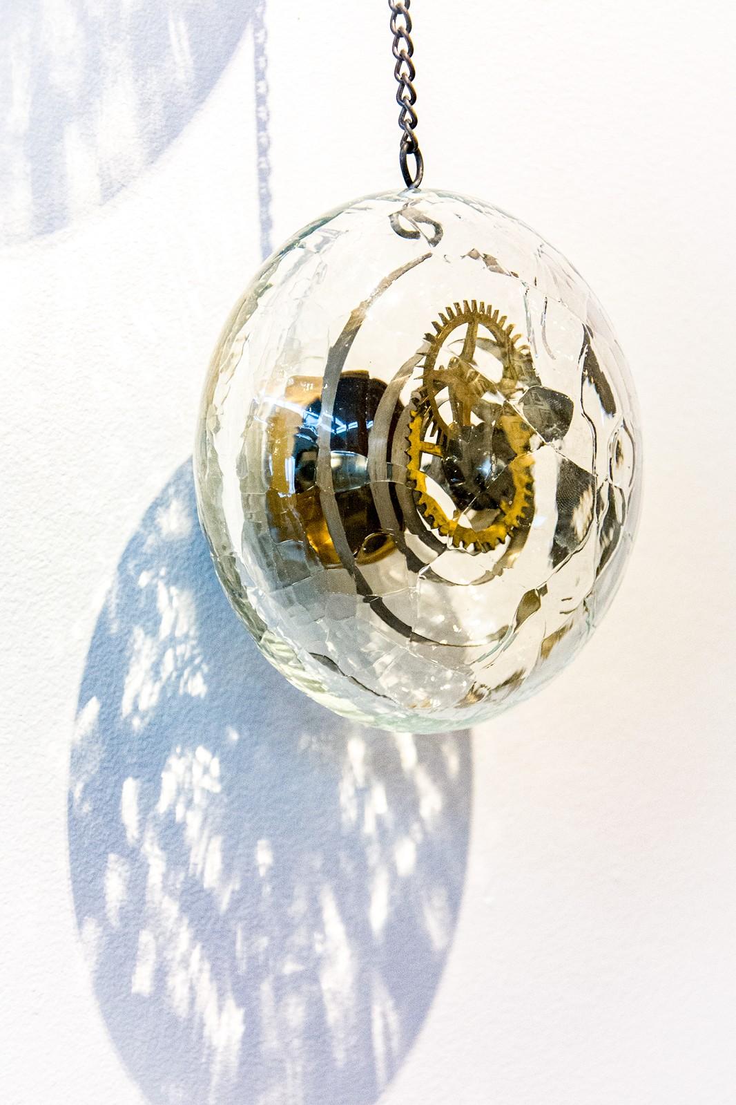 Vier elegante Glaskugeln, die zusammengesetzte Uhrwerke enthalten, hängen an einer feinen Kette in dieser einzigartigen Wandskulptur von John Paul Robinson. Die Kugeln in vier Größen sind durch ein bewusstes, feines Craquelé definiert und hängen in