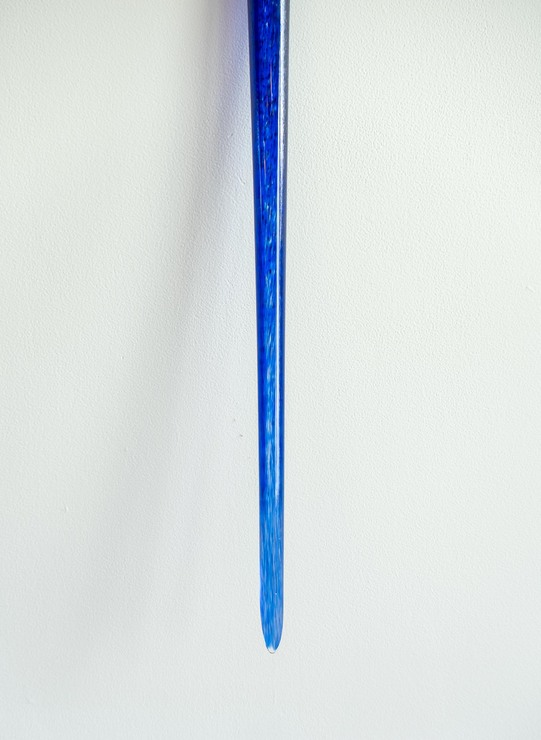 Cette sculpture murale contemporaine en verre d'un bleu profond est une œuvre de John Paul Robinson. Un seul tube de verre soufflé à la main, élégamment courbé, fait une déclaration dynamique lorsque la lumière joue sur sa surface translucide. De