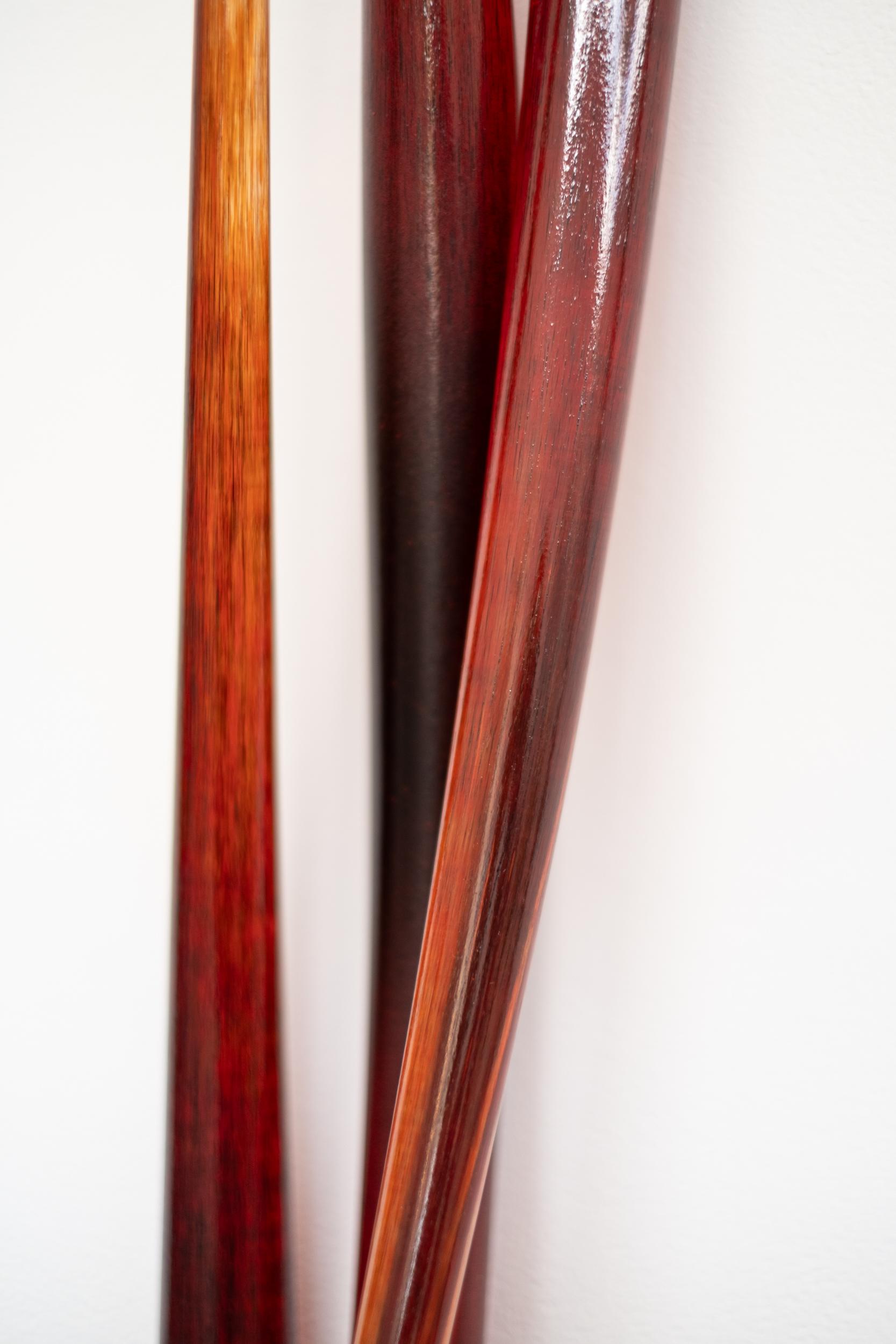 Diese moderne Wandskulptur aus Glas in Rot wurde von John Paul Robinson geschmiedet. Drei sanft gewölbte Glasröhren in einem tiefen Rot bilden eine anmutige Komposition, die an der Wand zu schweben scheint. Der kanadische Künstler nutzt seine