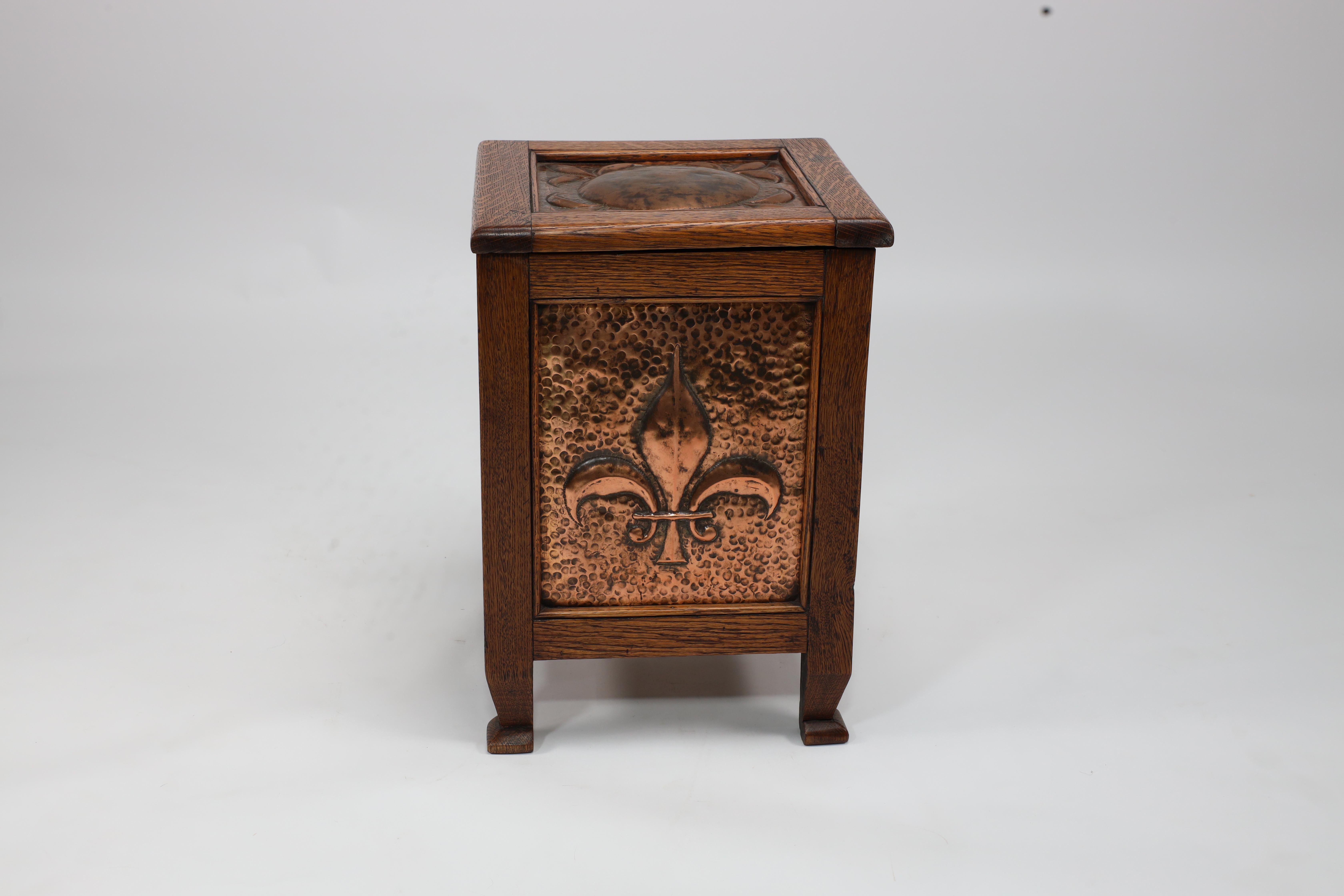 John Pearson attributed. An Arts and Crafts log or coal box with hand-formed circular Fluer De Lys copper panels to the top and larger Fleur De Lys to the sides.