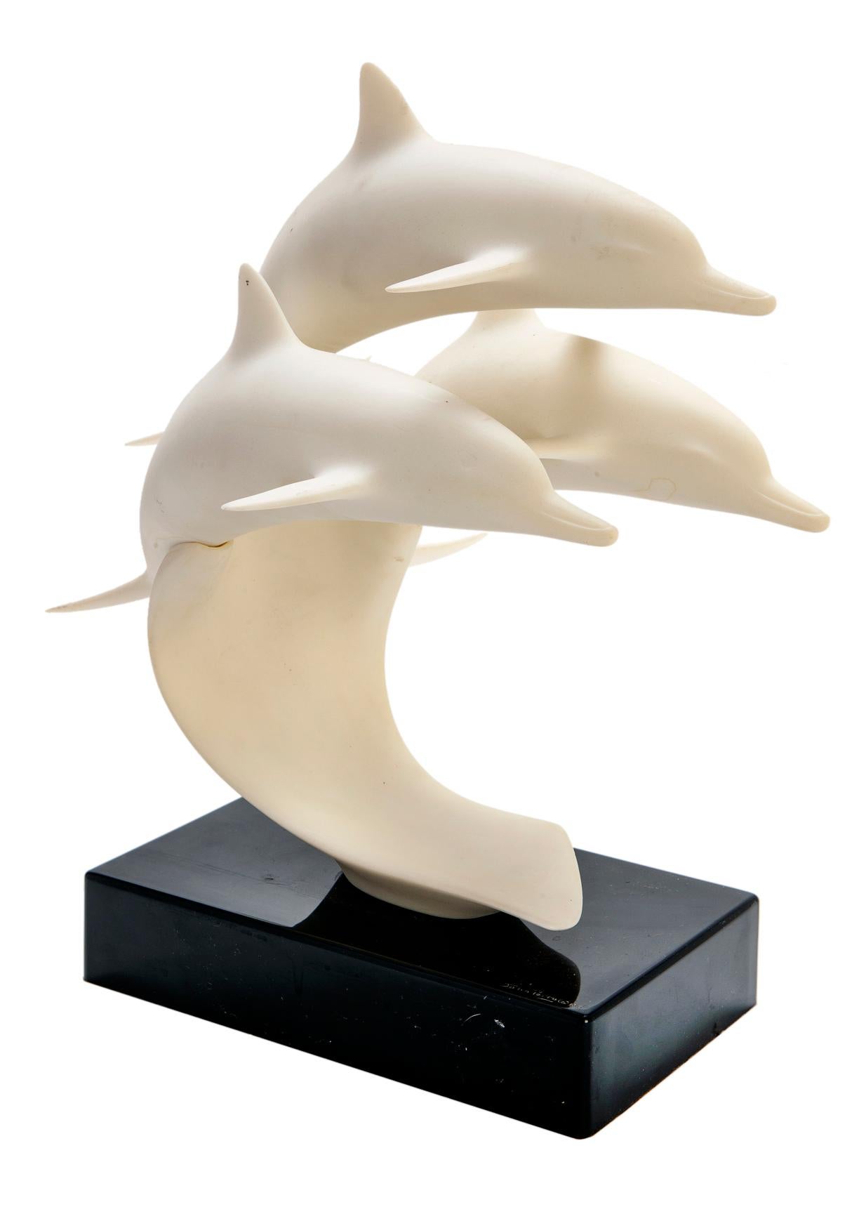 John Perry Scultura di tre delfini saltellanti su una base laccata nera.
Statuetta originale del delfino bianco di John Perry. Tre delfini che nuotano si trovano sopra una base laccata nera. La base è rara, dato che la maggior parte delle sculture