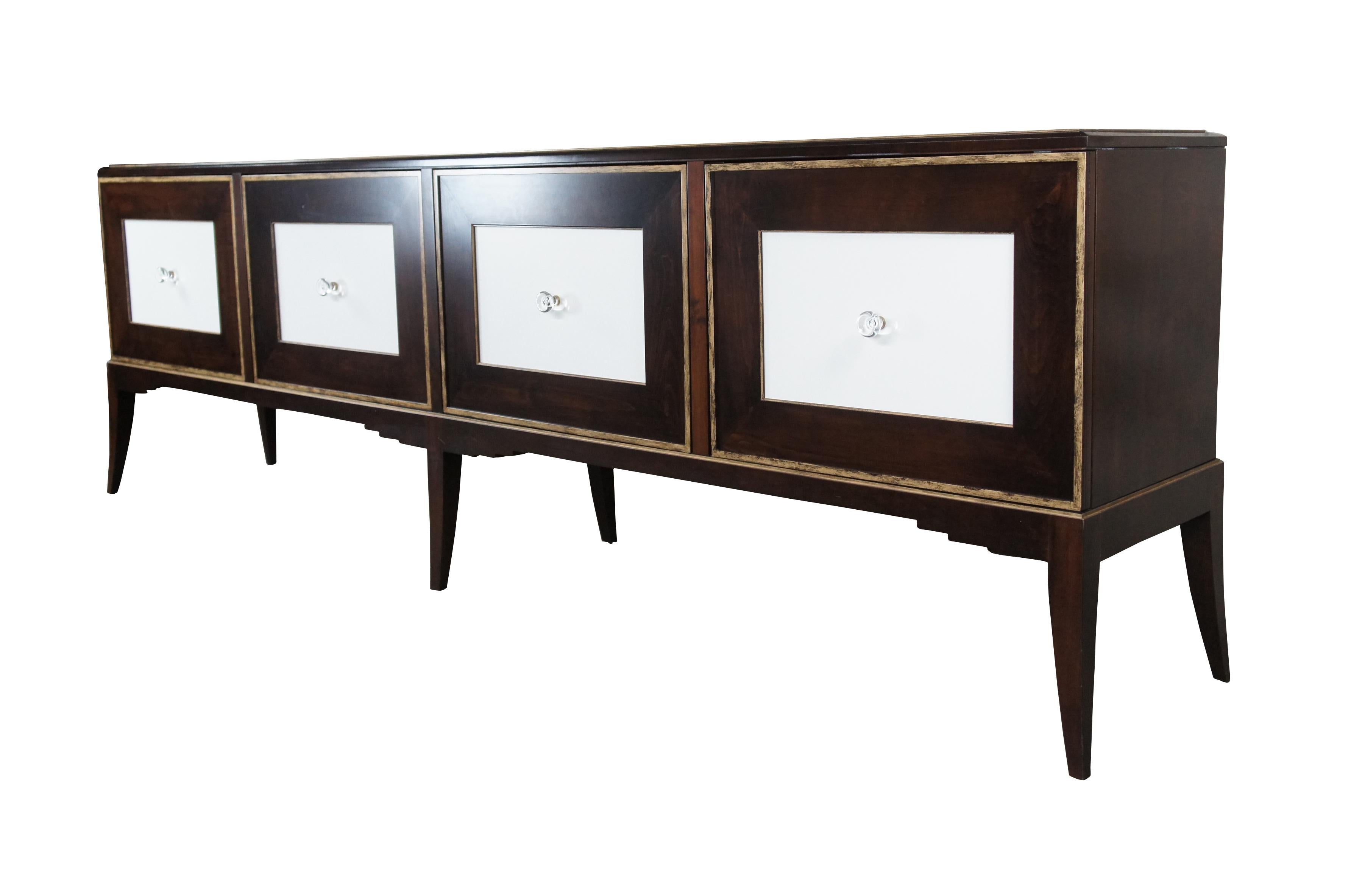 A large and impressive sideboard or credenza cabinet by John Richard.  Features a blend of Art Deco and Contemporary styling.  Made from Walnut with brushed gold finish along the doors and lower apron.  Features white inset panels with glass pulls. 