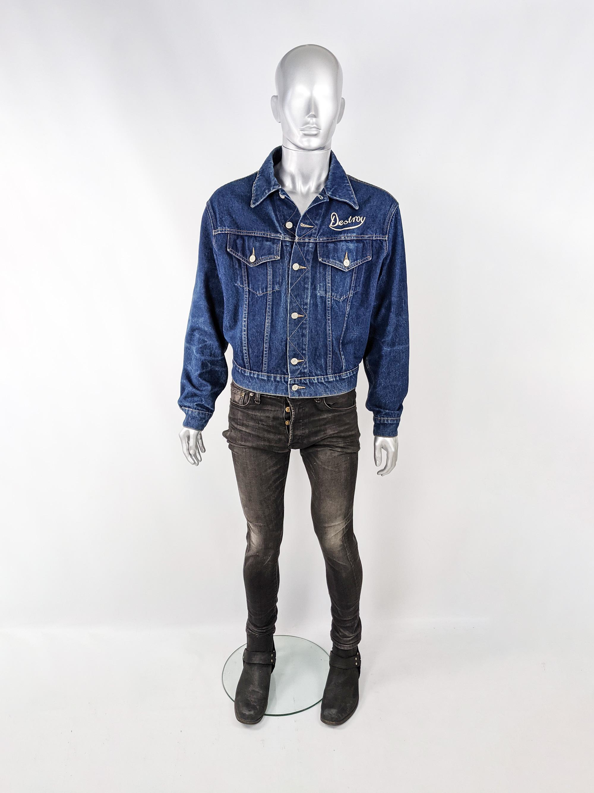 An amazing and rare vintage mens denim jacket from the early 90s by luxury British rock n roll fashion designer, John Richmond for his cult status Destroy line. In a blue denim with a black faux leather back emblazoned with a 'Nomad' and eagle