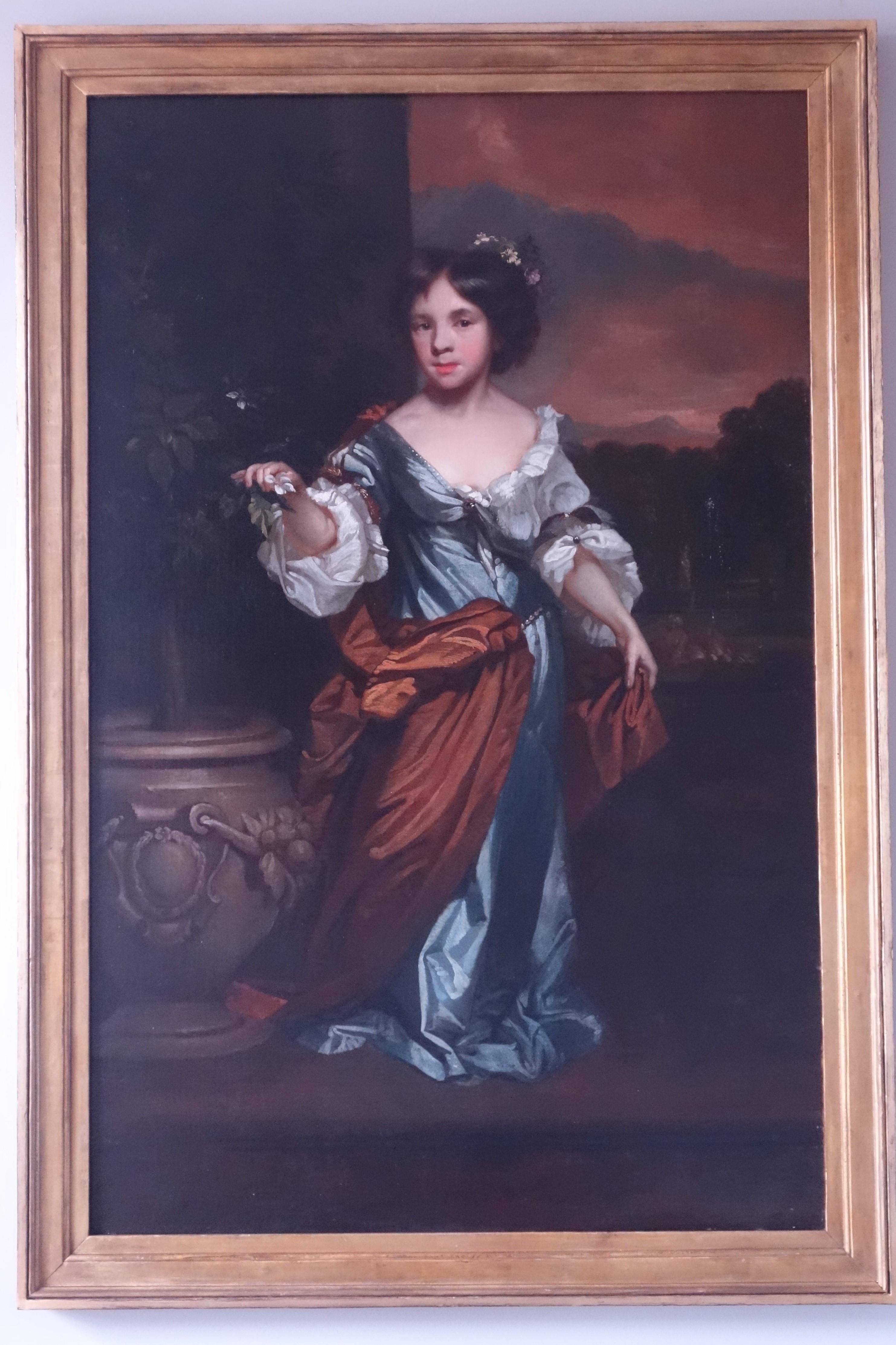 Retrato de una joven, de cuerpo entero, con un vestido de seda azul, de pie en una terraza junto a una urna clásica que sostiene una rama en flor. Atribuido a John Riley (1646-1691). Óleo sobre lienzo, en marco de madera dorada cassetta de época.