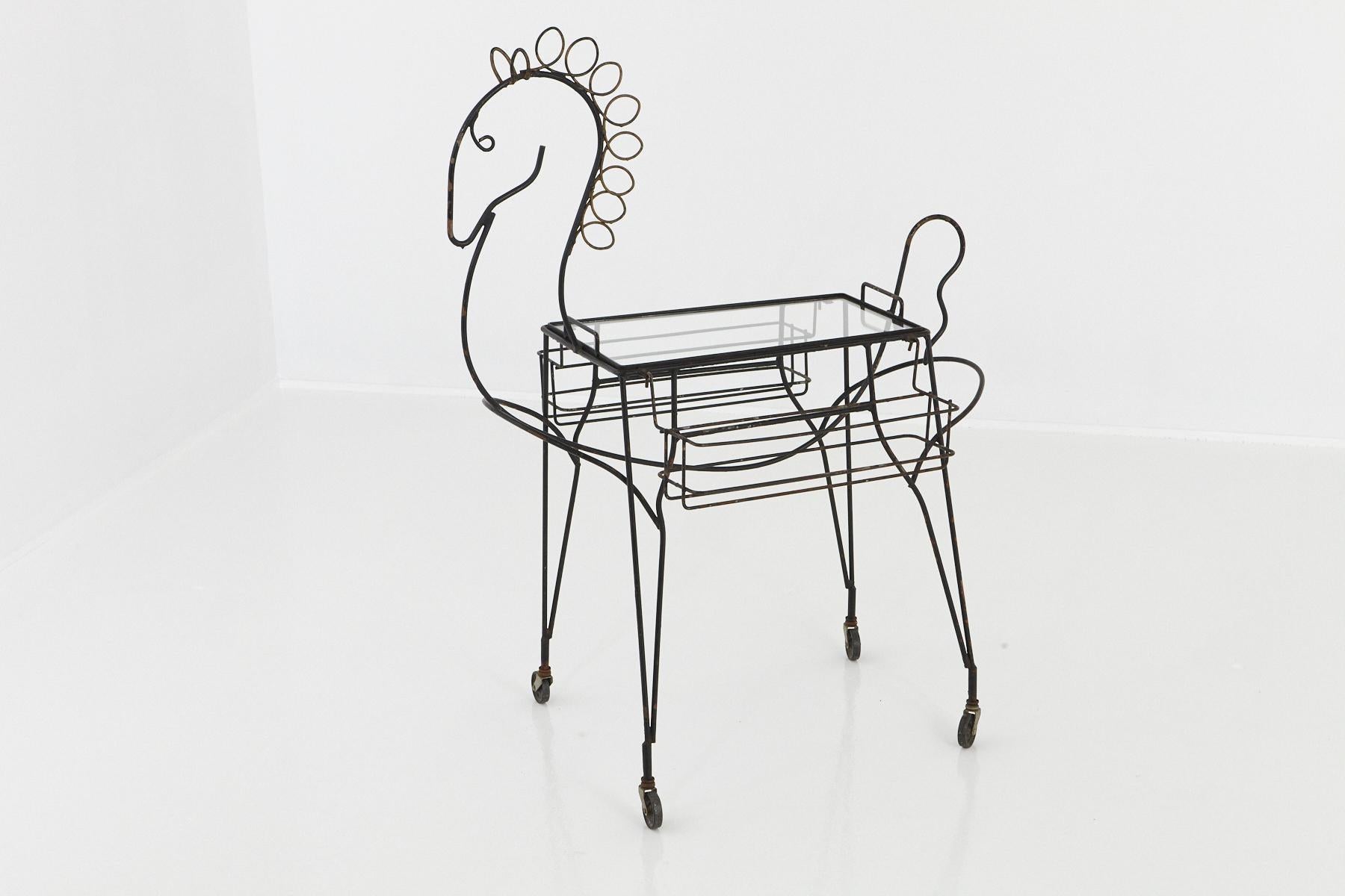 Chariot de bar en fer forgé noir John Hollister Risley (1919-2002) au design de cheval, avec deux porte-bouteilles amovibles de chaque côté et un plateau en verre amovible sur roulettes, vers 1955.
Le « chariot de bar à cheval » est en très bon
