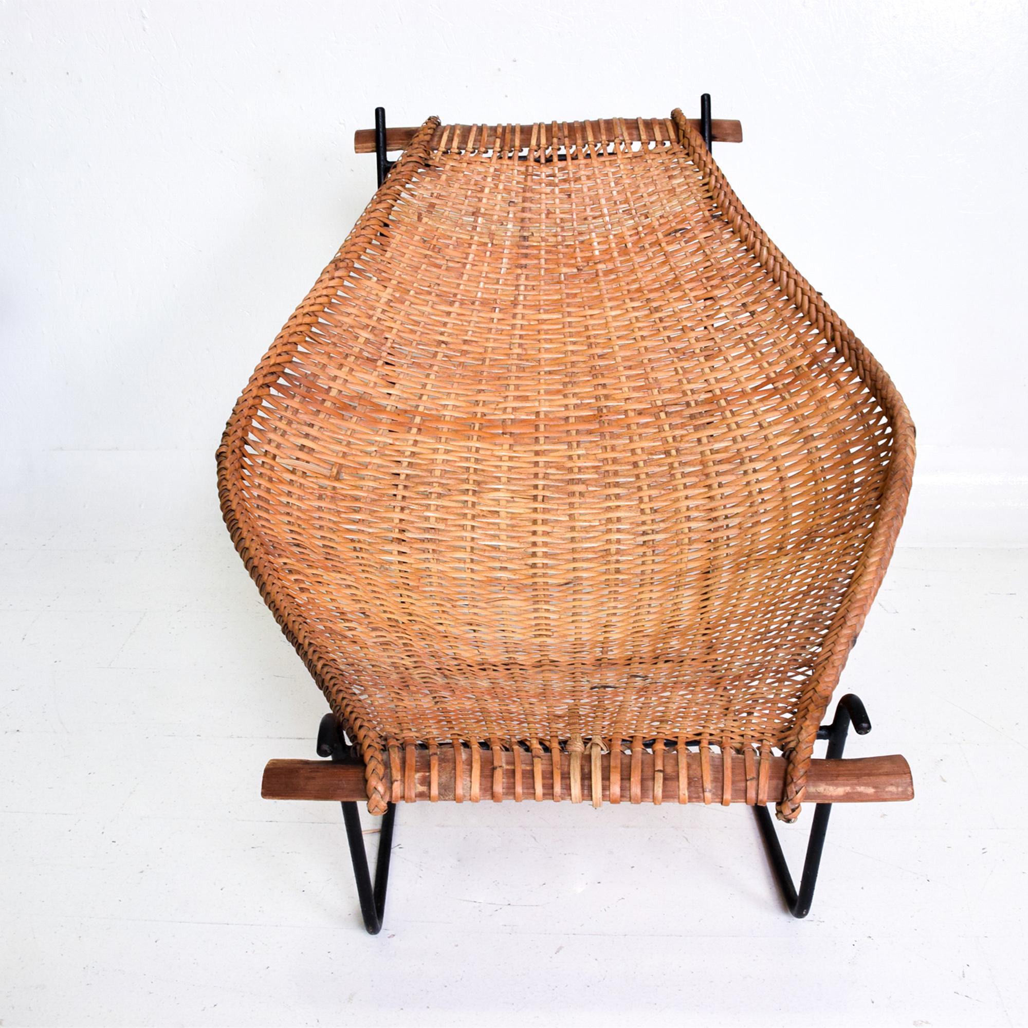 John Risley designer of the modernist Duyan: Relaxed handwoven rattan & iron lounge chair.
Minimal iron frame supports a curved cane sling finished braided edge with bamboo supports. 
Wonderful weaving craft & modern midcentury design from USA