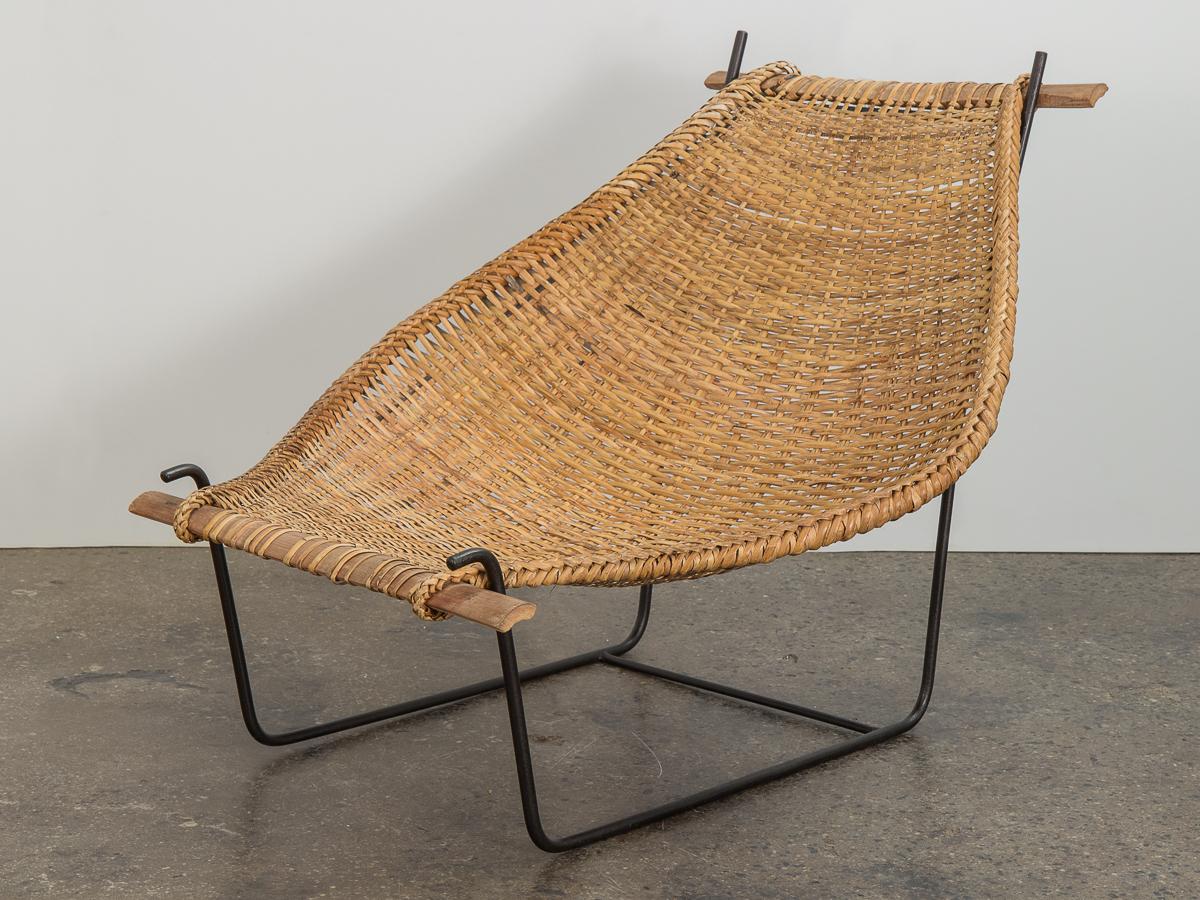 Modernist Duyan lounge chair designed by John Risley. Minimal iron frame supports a curved sling, finished with a beautiful braided edge. Bamboo supports at each end. A delightful mélange of traditional weaving craft and modern design. The chair is