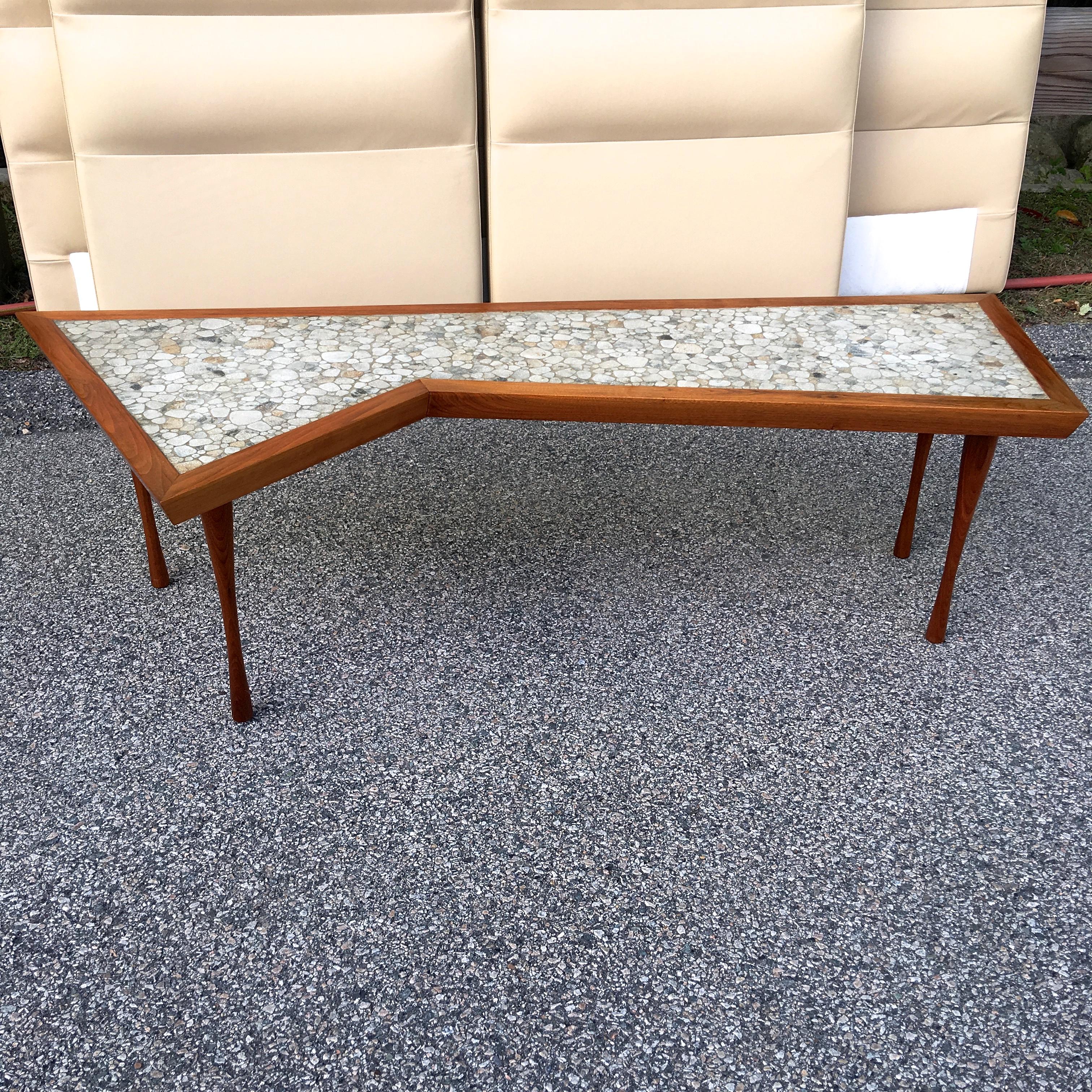 An artfully constructed walnut framed cocktail table in asymmetric rectangular form inset with irregular sized pebble shaped glazed stoneware tiles, standing on four organically turned walnut legs in the style of Paul McCobb. Signed John Rothschild