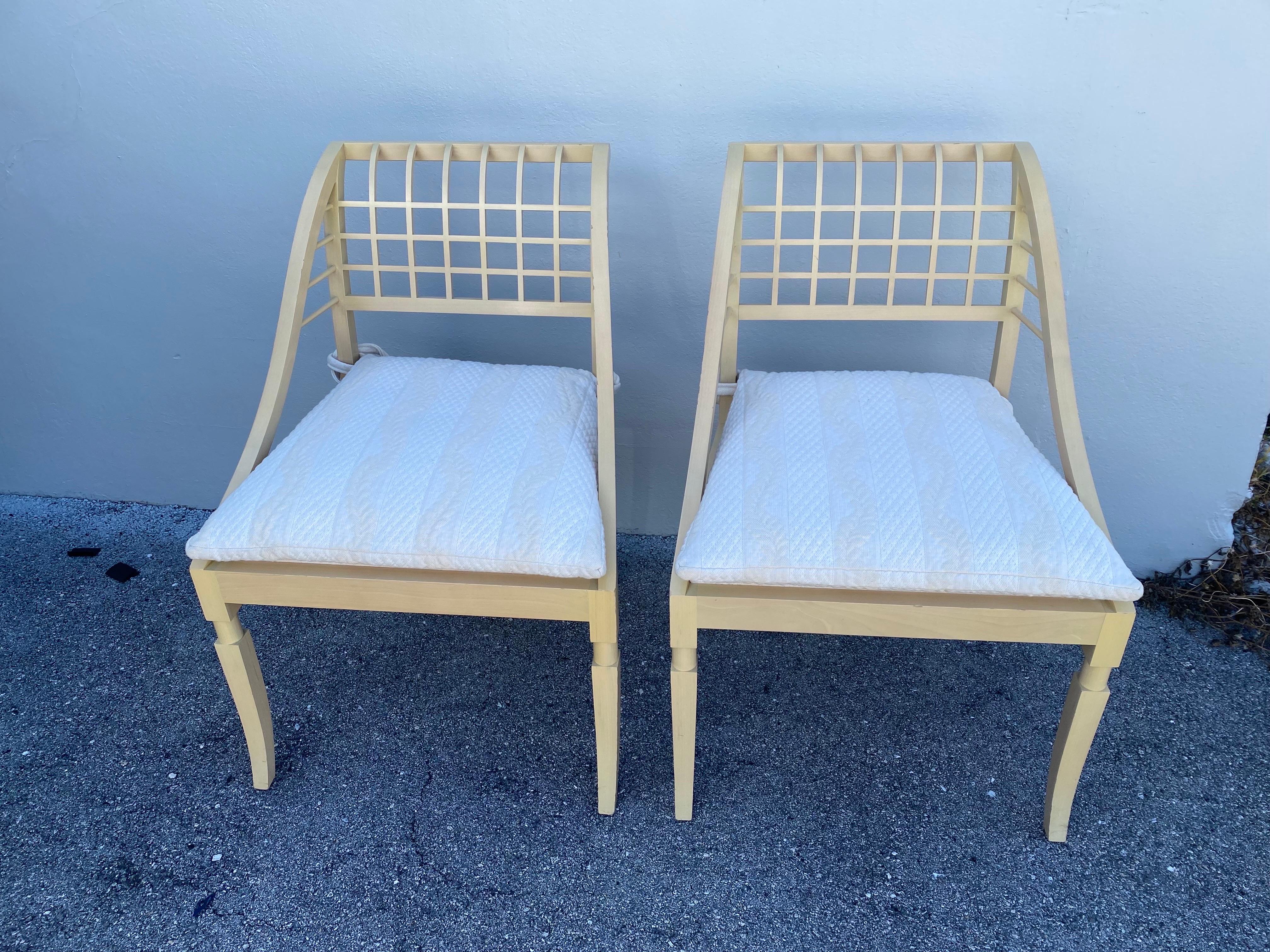 Pair of vintage (as found) John Saladino (b. 1939) sleigh chairs., featuring a muted yellow hue wood frame and lattice backrest. Included are tie-back white seat cushions. Showing wonderful craftsman style details.  THIS ITEM IS LOCATED AND WILL