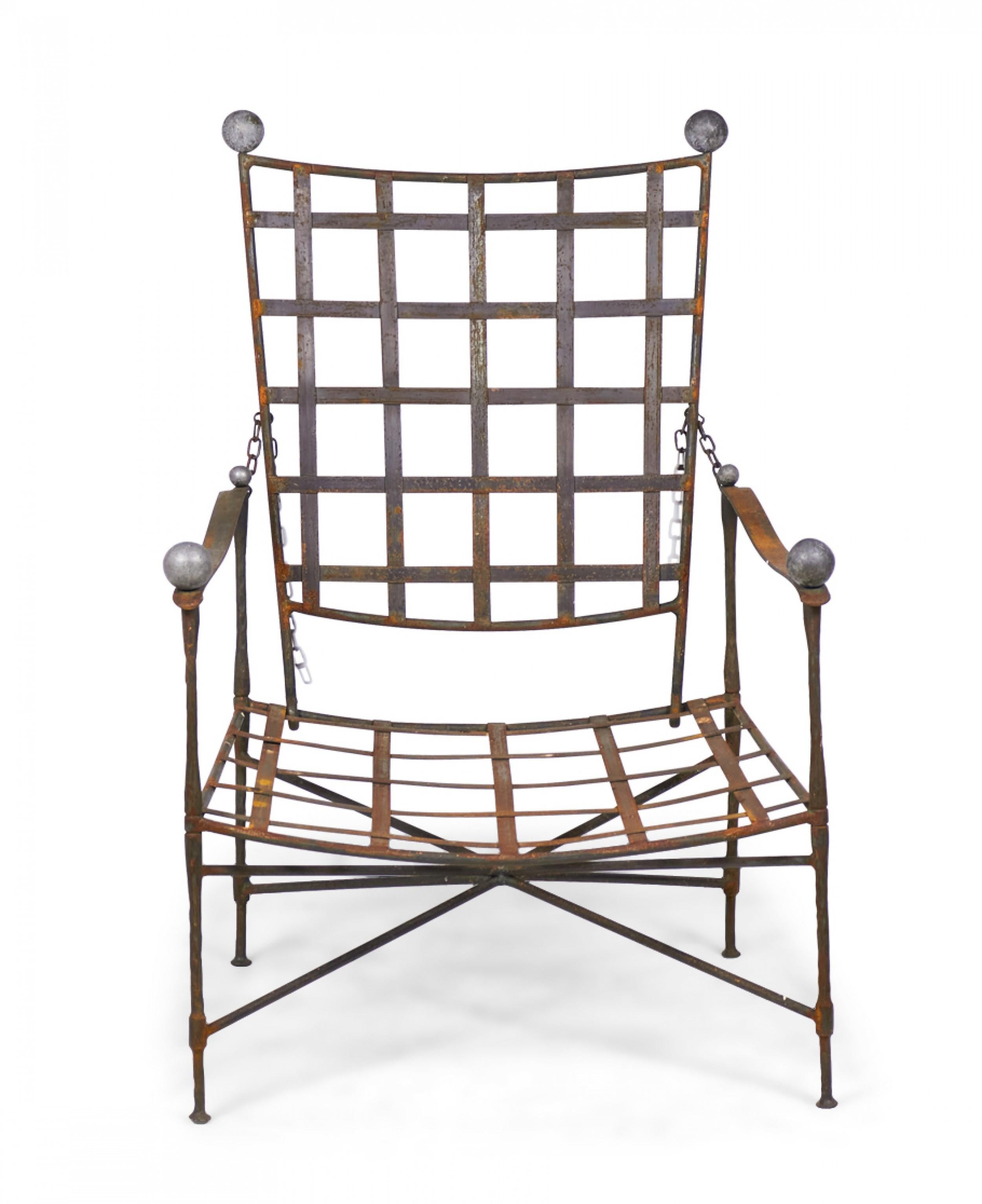 American mid-century outdoor adjustable reclining lounge / armchair with a latticed back and seat supported in an iron frame with ball finials on the chair back corners and armrests, resting on four straight iron legs connected by a stretcher base.