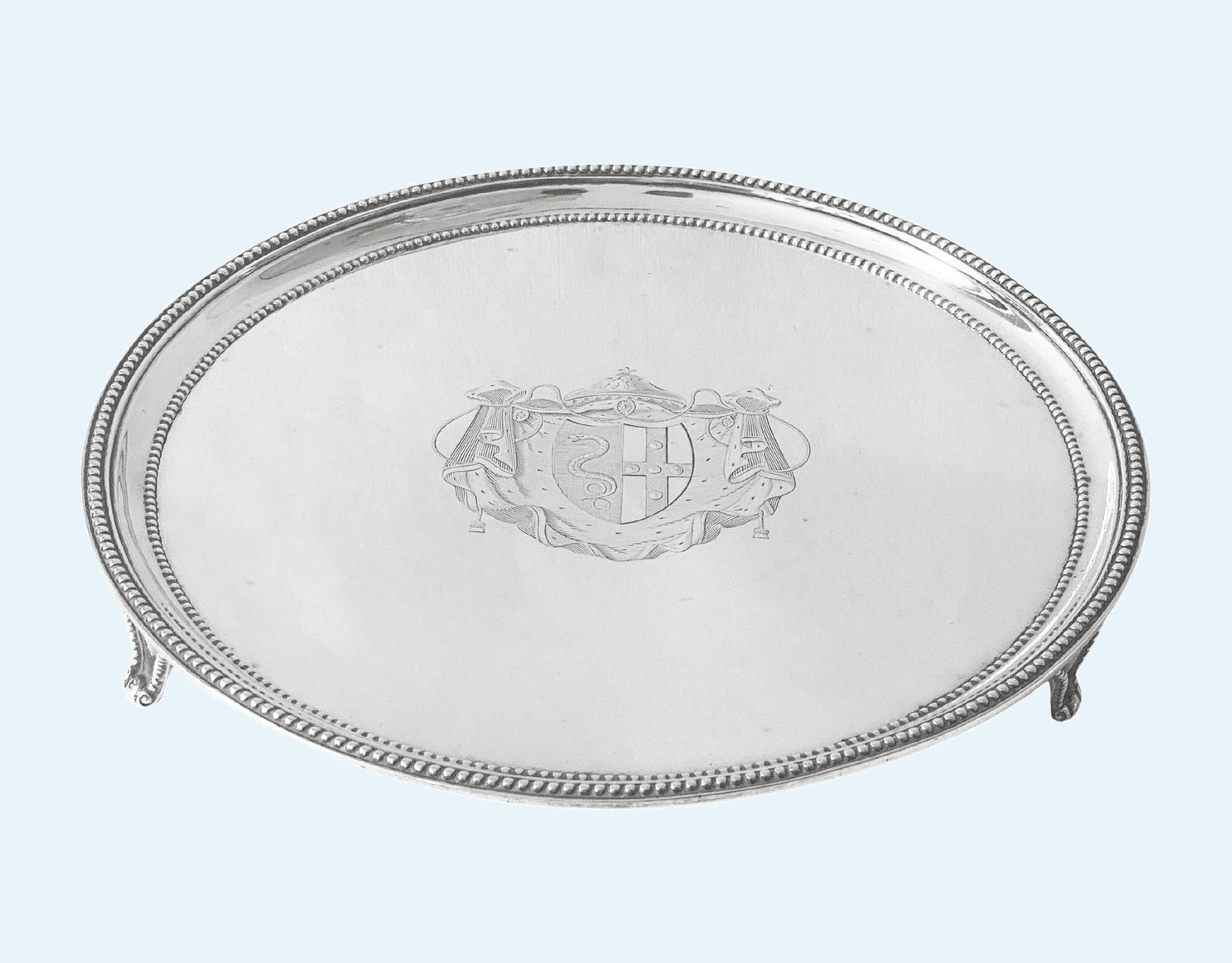 Bandeja de plata georgiana antigua Londres 1785 John Scofield 1785. Ensaladera de forma circular con borde e interior en relieve, escudo familiar en el centro, elevada sobre tres pies, con matasellos. Peso: 478 gramos Diámetro: 9 pulgadas. Altura: