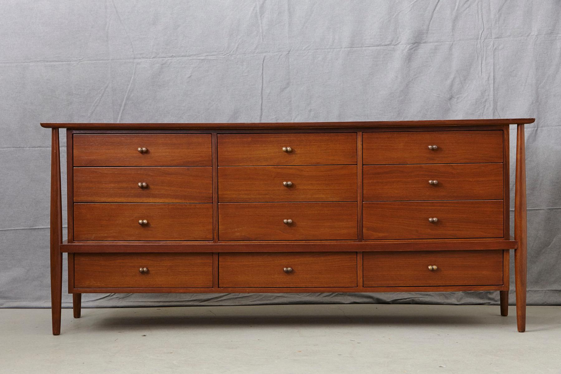 John Stuart 12 drawers walnut dresser with original solid brass pulls mounted on tapered legs, 1960s.
The 6 ft. long credenza has a very elegant and light appearance because of the sculptured looking legs.
The credenza is in very good condition,