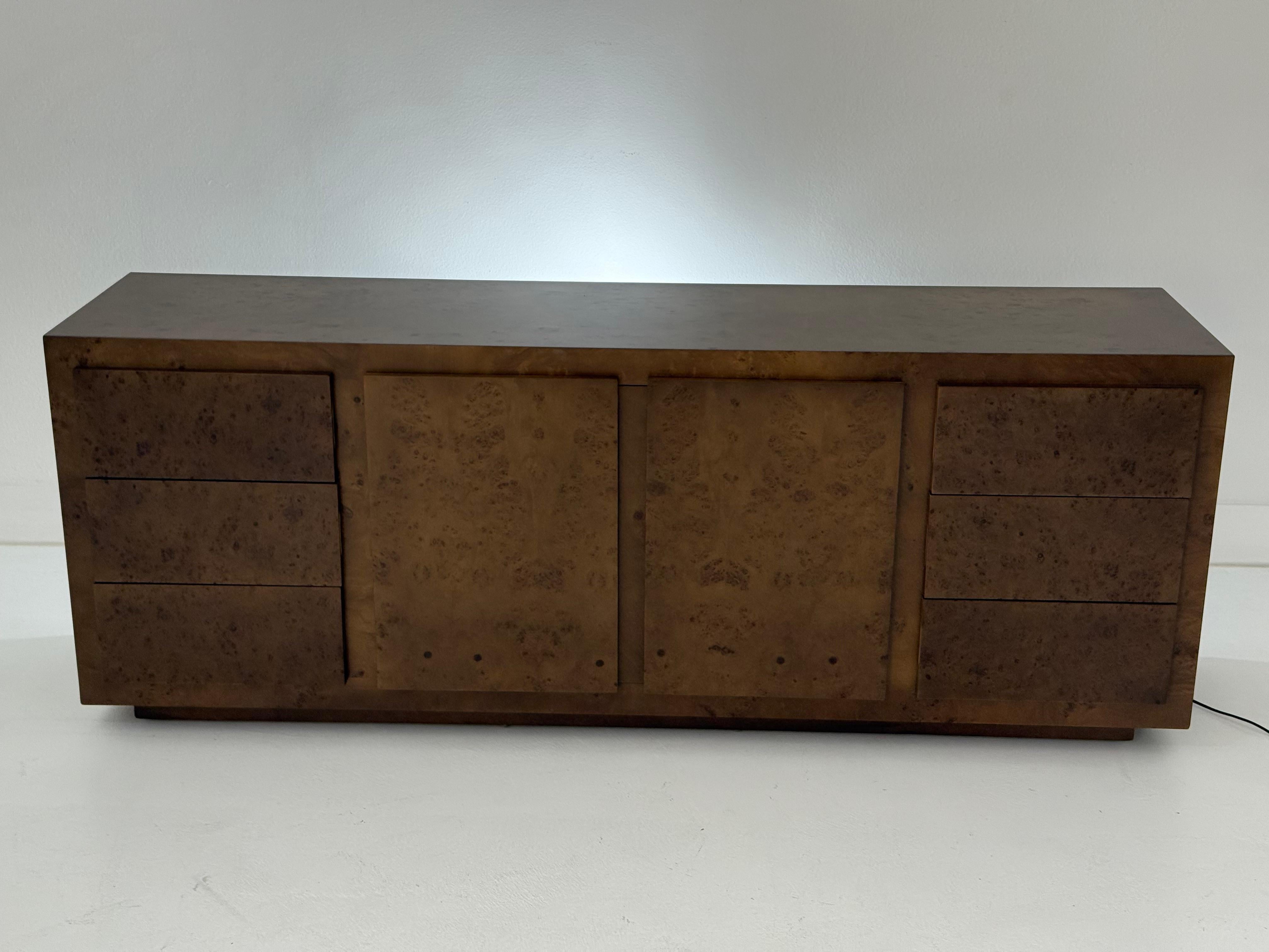 Exemple frappant du design américain des années 1970, cette commode ou armoire vintage est fabriquée en bois ronceux magnifiquement figuré et signée par John Stuart. La forme rectangulaire épurée est rehaussée par le riche motif naturel du grain du