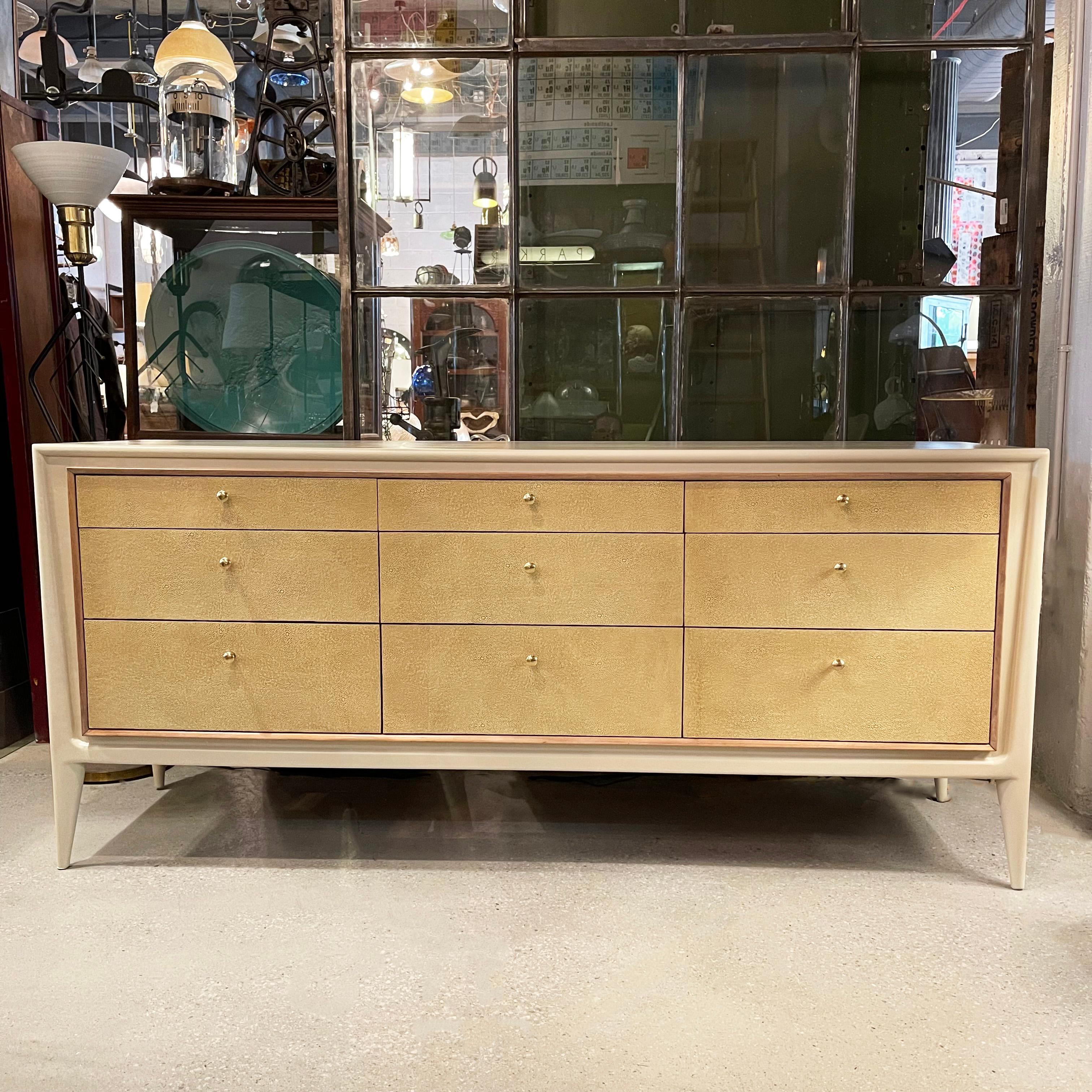 Mid-Century Modern, triple wide, walnut dresser by John Stuart, Facade features a surround lacquered in cream, drawer fronts covered in tan shagreen leather with brass pulls and a natural mahogany trim. The custom finish really pronouces all the