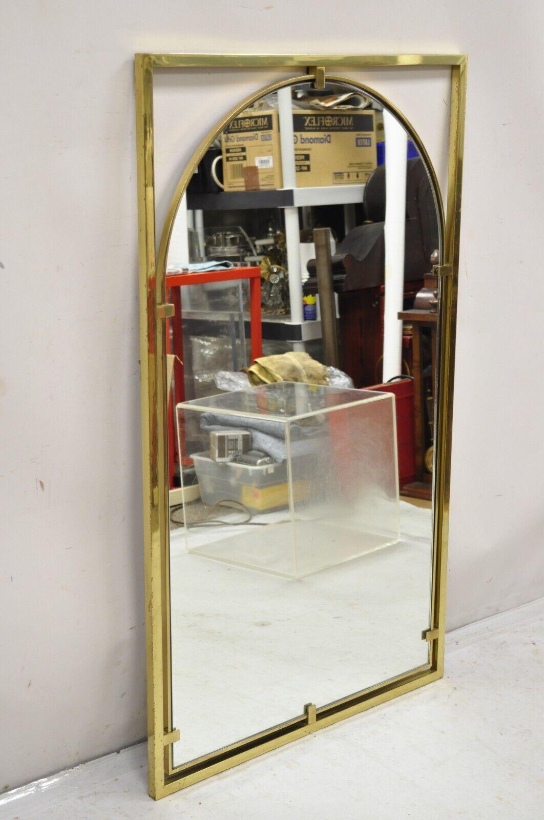 Vintage Hollywood Regency Brass Frame Arched Glass Modernist Wall Mirror by John Stuart. Circa  Mid to Late 20th Century.
Measurements: 47
