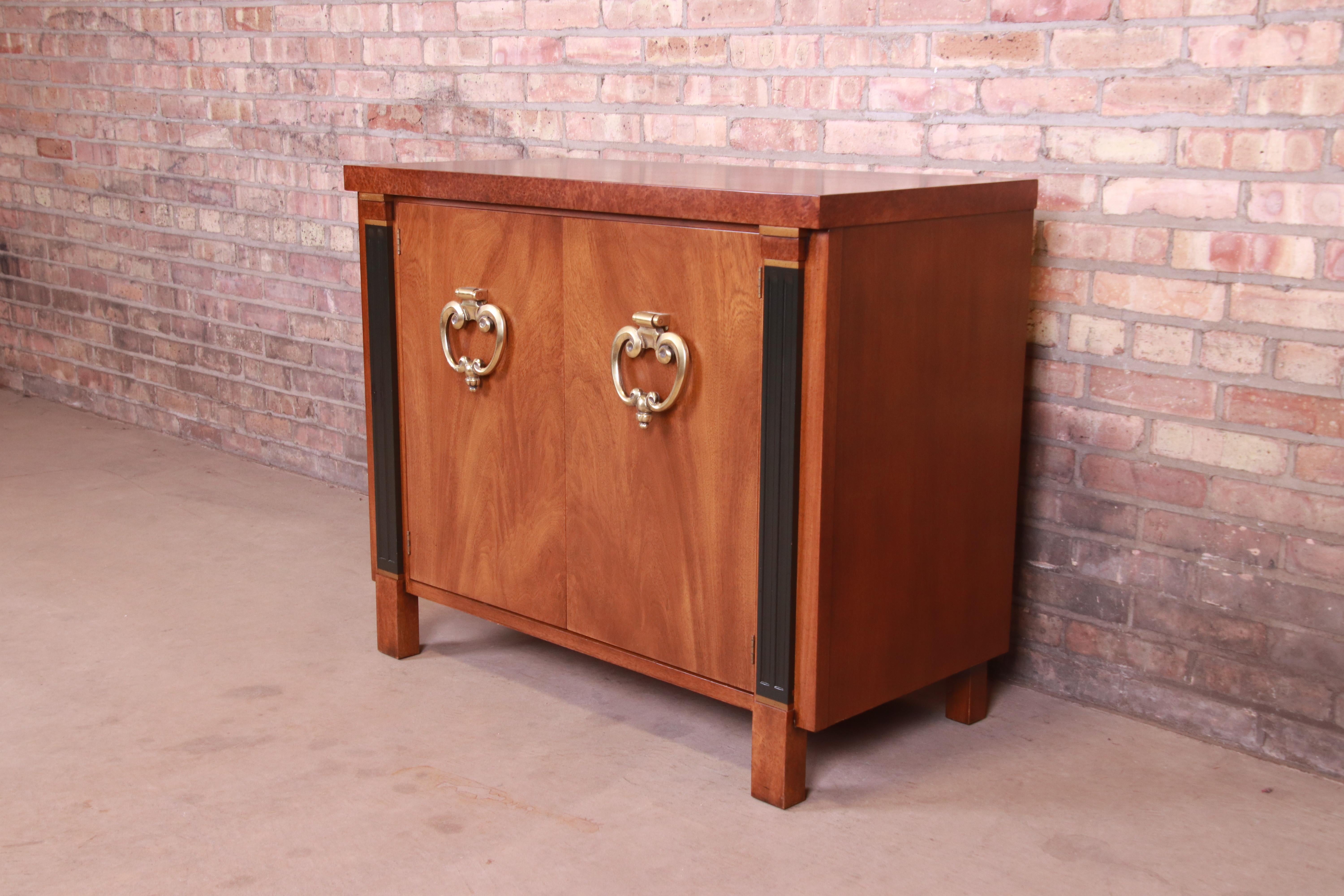 An outstanding mid-century Hollywood Regency buffet server, compact credenza, or bar cabinet

Produced by Johnson Furniture for John Stuart

USA, Circa 1960s

Book-matched walnut, with burled walnut trim, ebonized columns, and original brass