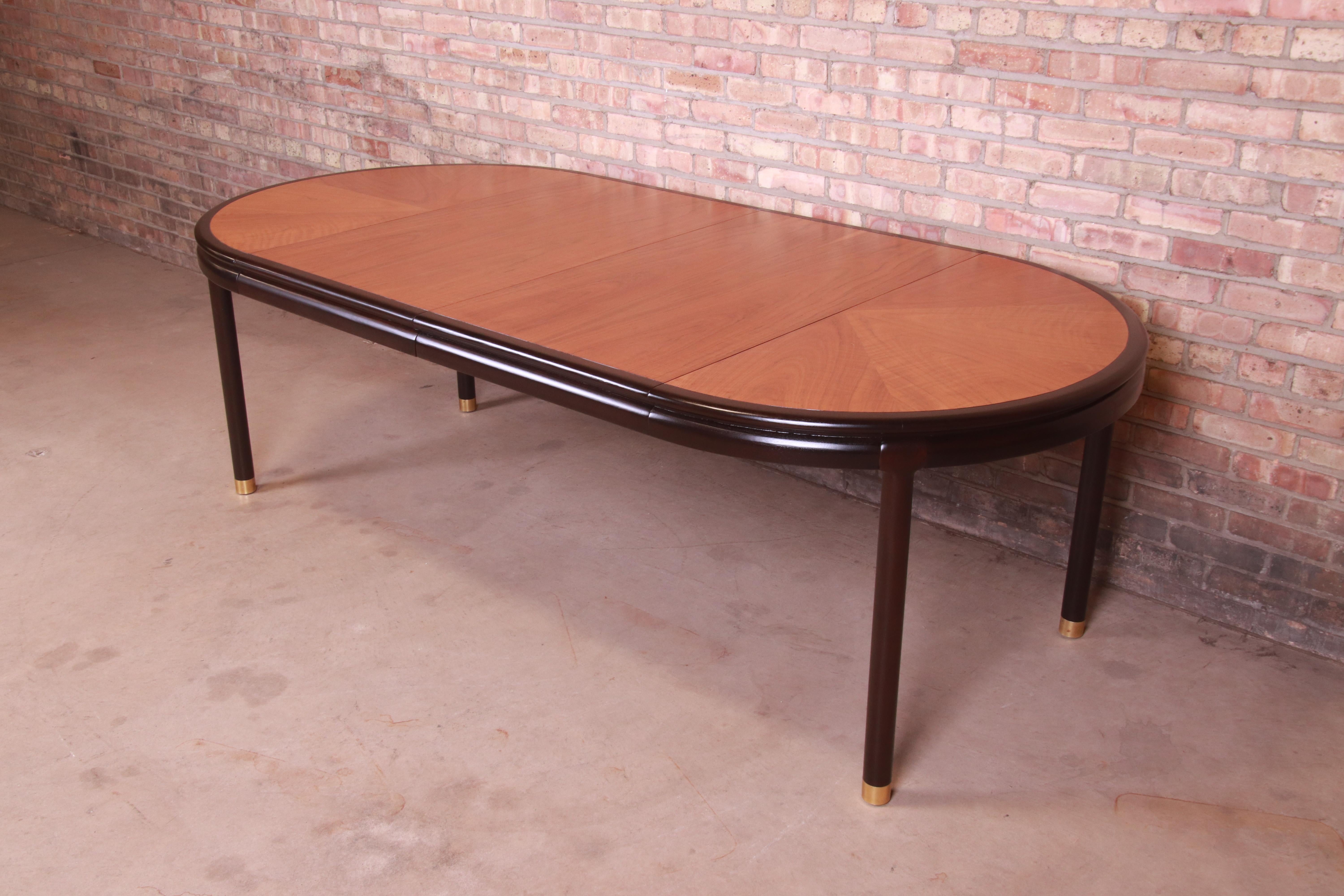 An exceptional mid-century modern extension dining table

By John Stuart

USA, 1950s

Book-matched teak wood top, with ebonized banding and legs and brass-capped feet.

Measures: 44