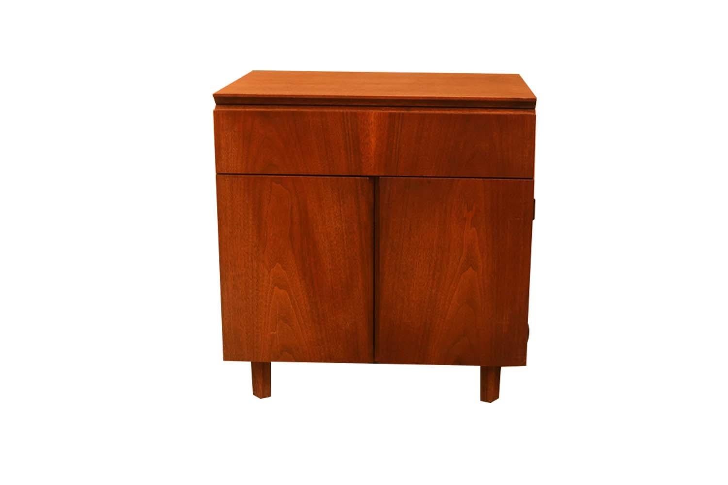 A stunning Mid-Century Modern side table or nightstand designed by John Stuart for Johnson Furniture Co. in the United States, circa 1960s. Pure style and sophistication, featuring a single spacious drawer above a double door cabinet that opens to