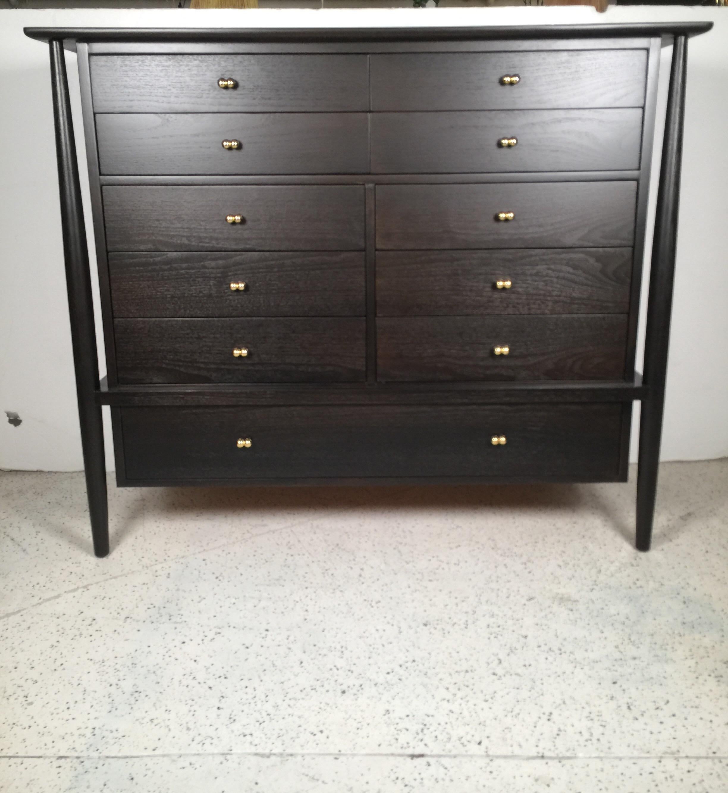 A sculpted dresser that completes any room, featuring 11 ebonized drawers studded with solid brass handles.