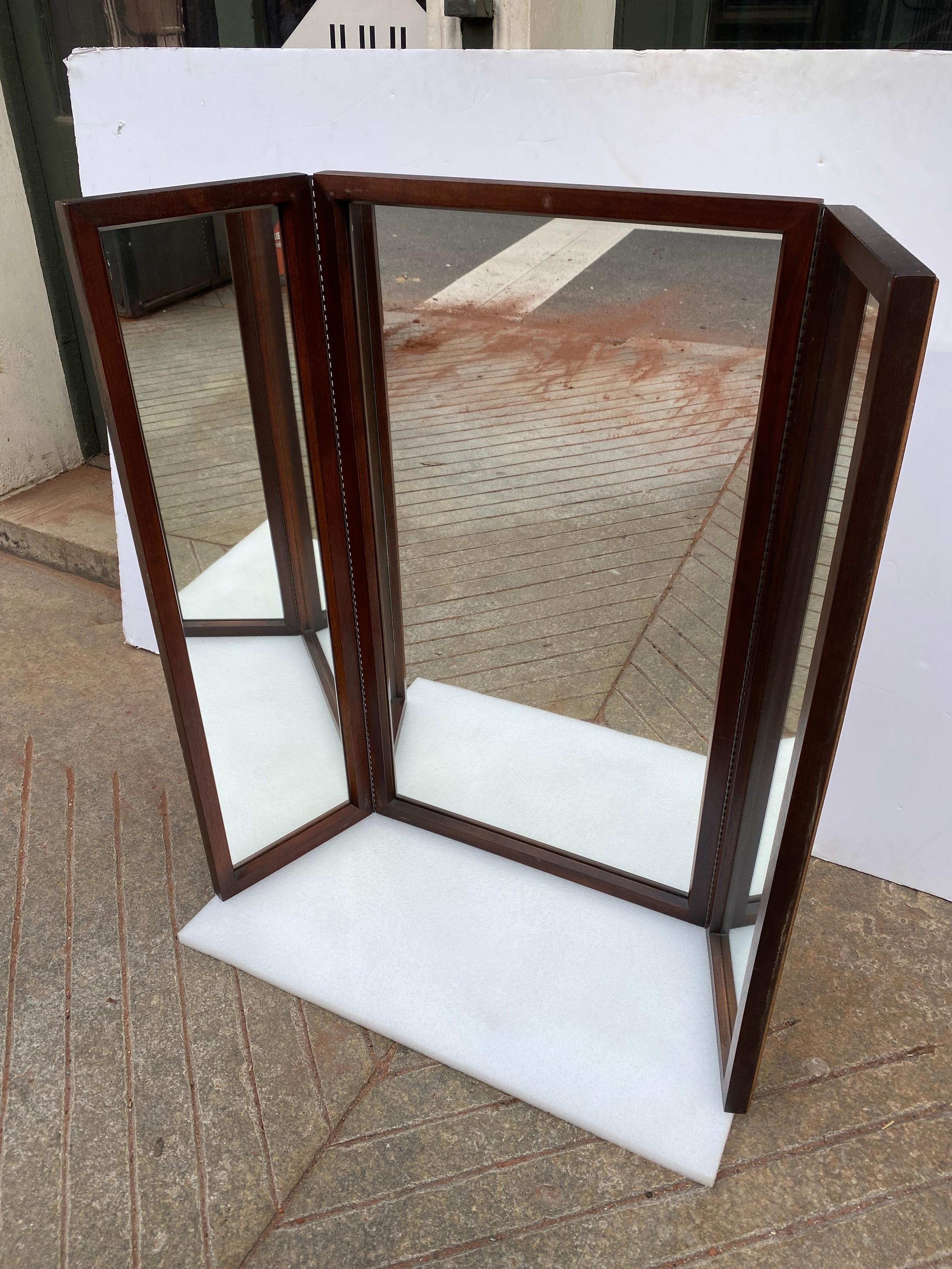 John Stuart Walnut Tri-Fold Mirror.  Hooks are mounted on the center mirror which allows the hinged ends to fold towards or away from you.  Nice Condition!  Ready to hang!