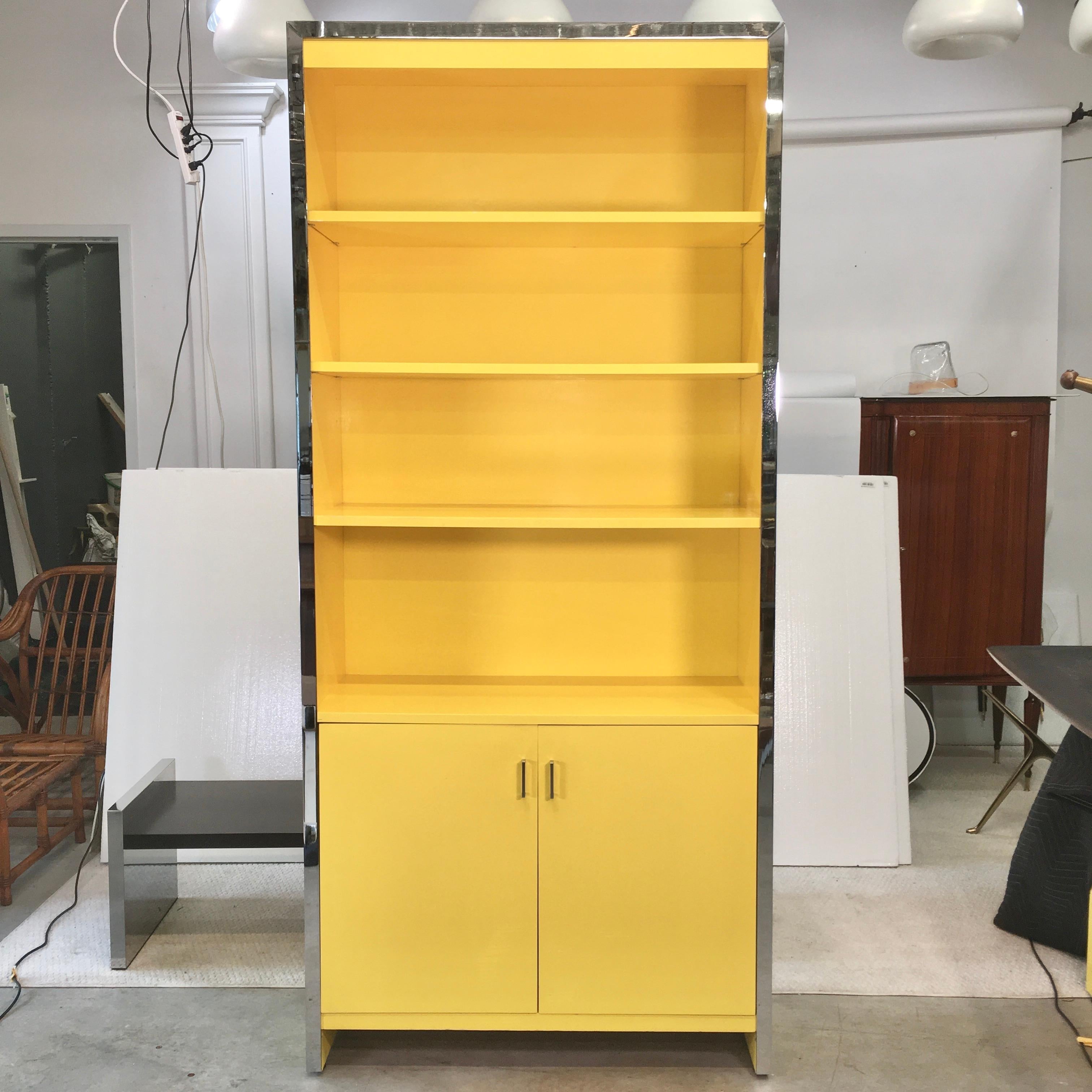 Cheerful and well proportioned tall bookcase cabinet which can also serve as a dry bar.
A hefty band of polished chromed steel along three front edges.
Three adjustable height shelves above a double door cabinet in which is a single adjustable